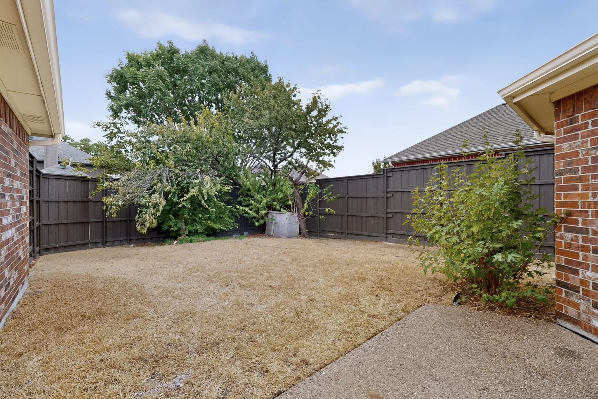 Private backyard featuring a concrete patio, wood privacy fencing, and mature trees