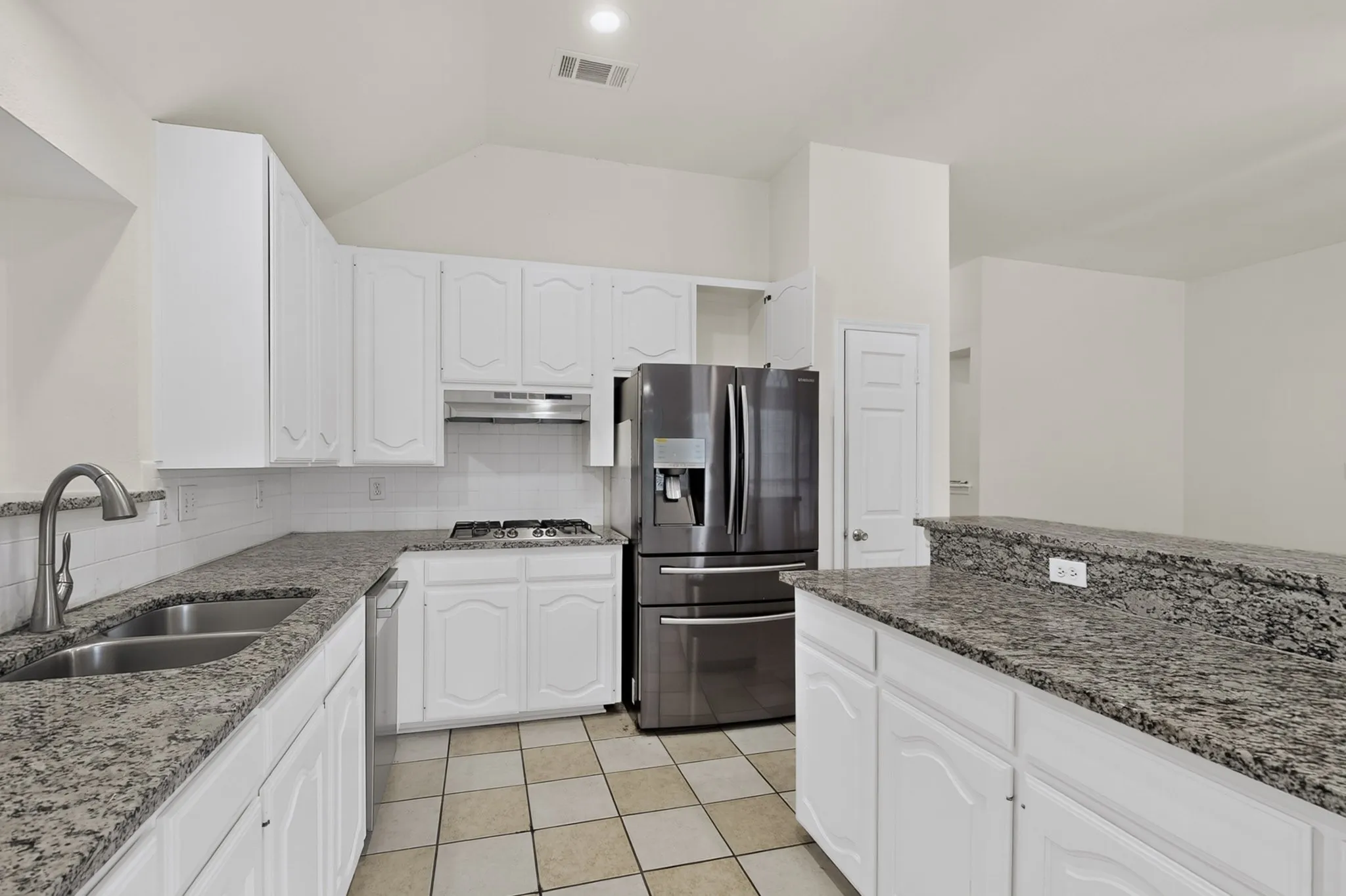 Kitchen featuring white cabinetry, speckled countertops, a double basin stainless steel sink, and stainless steel appliances