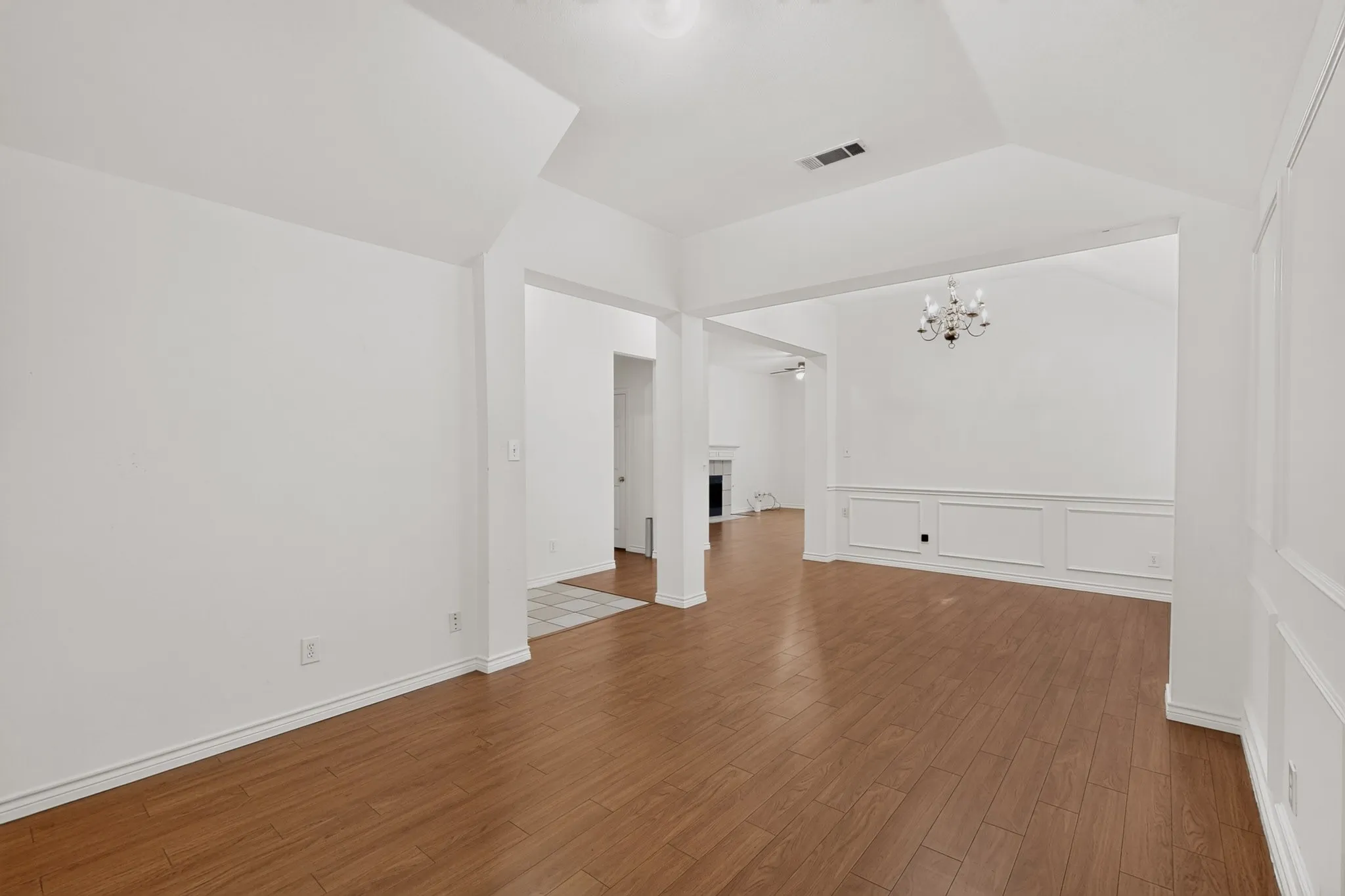 Wood-finish flooring, vaulted ceilings, wainscoting, and a chandelier