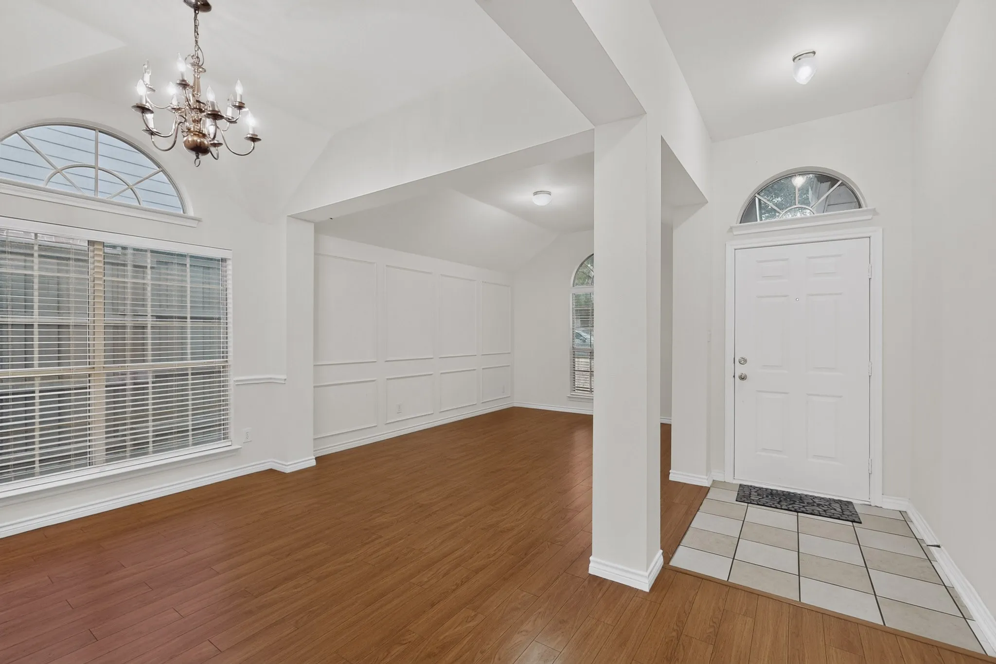 Entryway featuring a tiled landing, arched transom window, and wood-finish flooring
