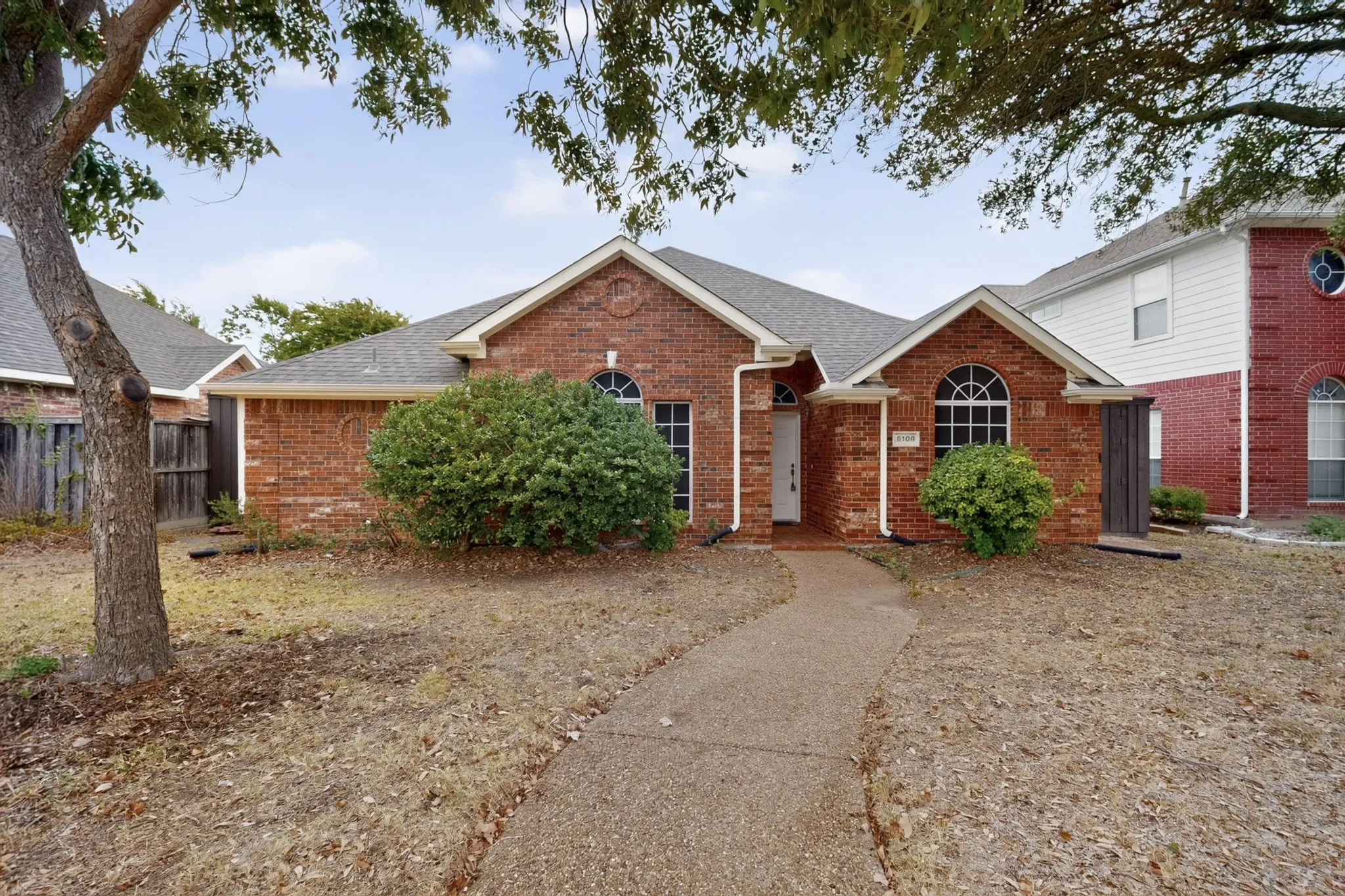 Brick exterior featuring a gabled roofline, arched windows, and a concrete pathway
