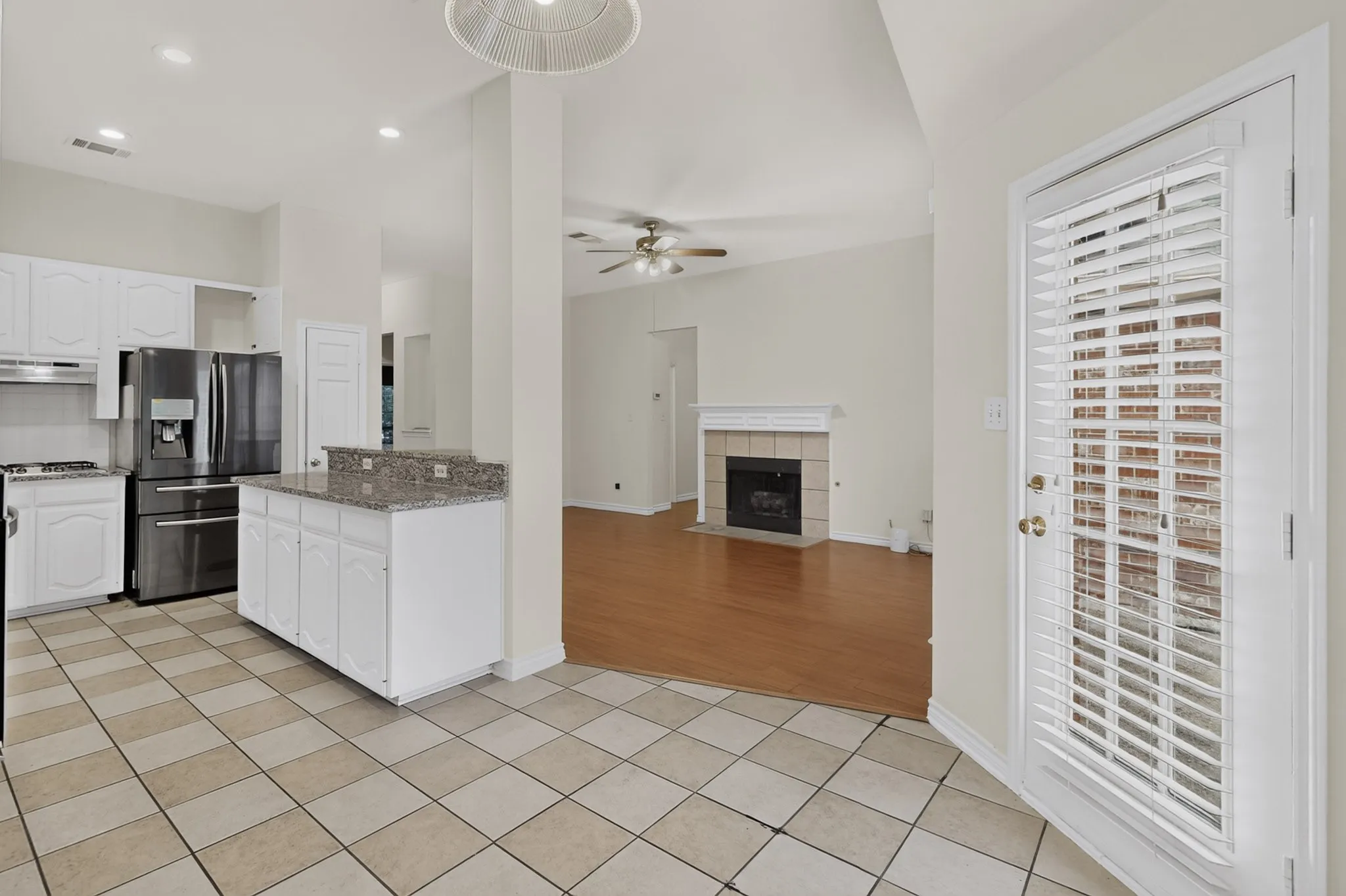 Kitchen featuring white cabinetry, stainless steel appliances, granite countertops, and tiled flooring