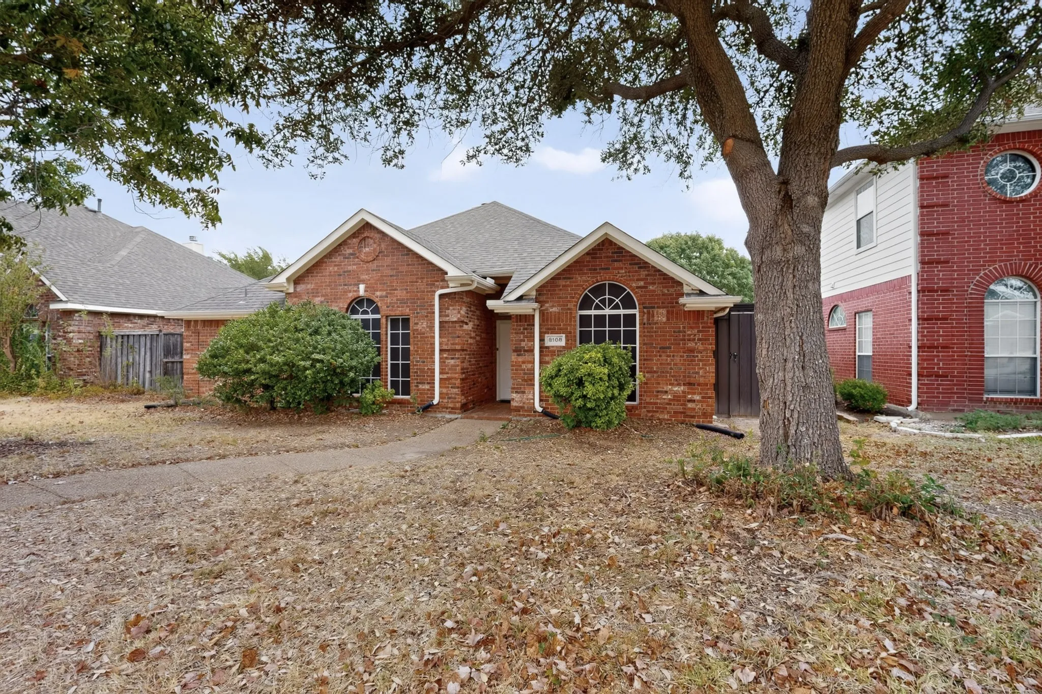 Brick exterior with arched windows, prominent gables, and a mature shade tree