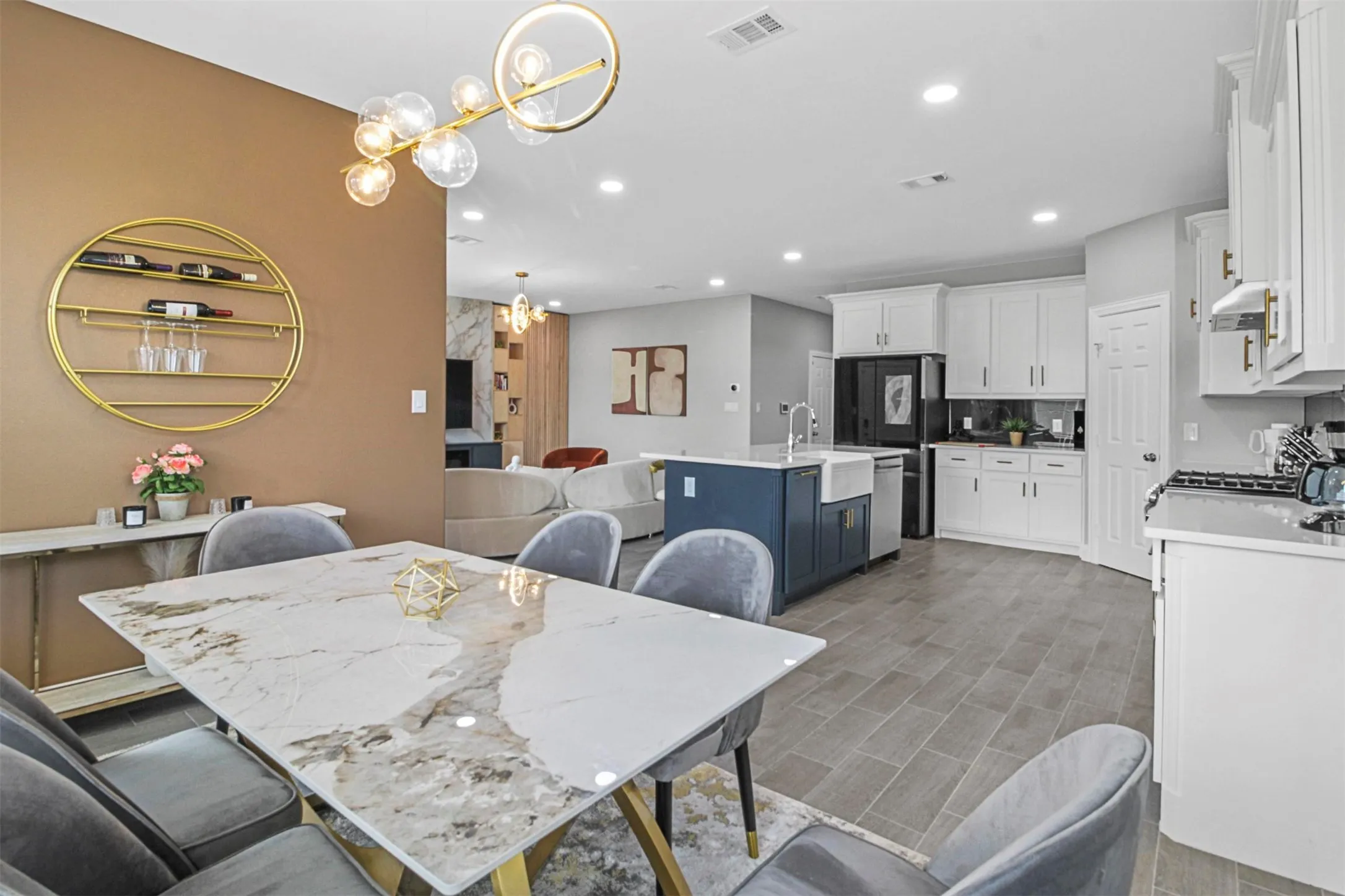 Open-concept living area with a contemporary chandelier, white kitchen cabinetry, a blue kitchen island, a farmhouse sink, and tile flooring