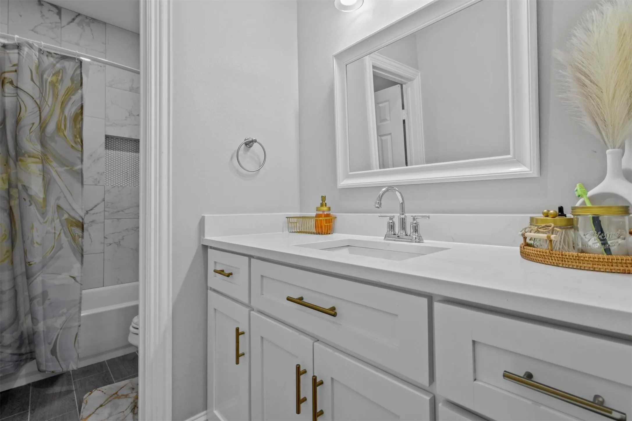 White vanity with gold hardware, recessed sink, and white countertop