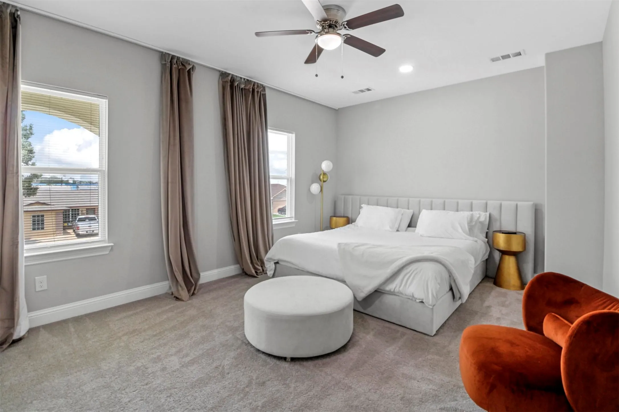 Carpeted flooring, two windows with window treatments, recessed lighting, ceiling fan, and a paneled headboard