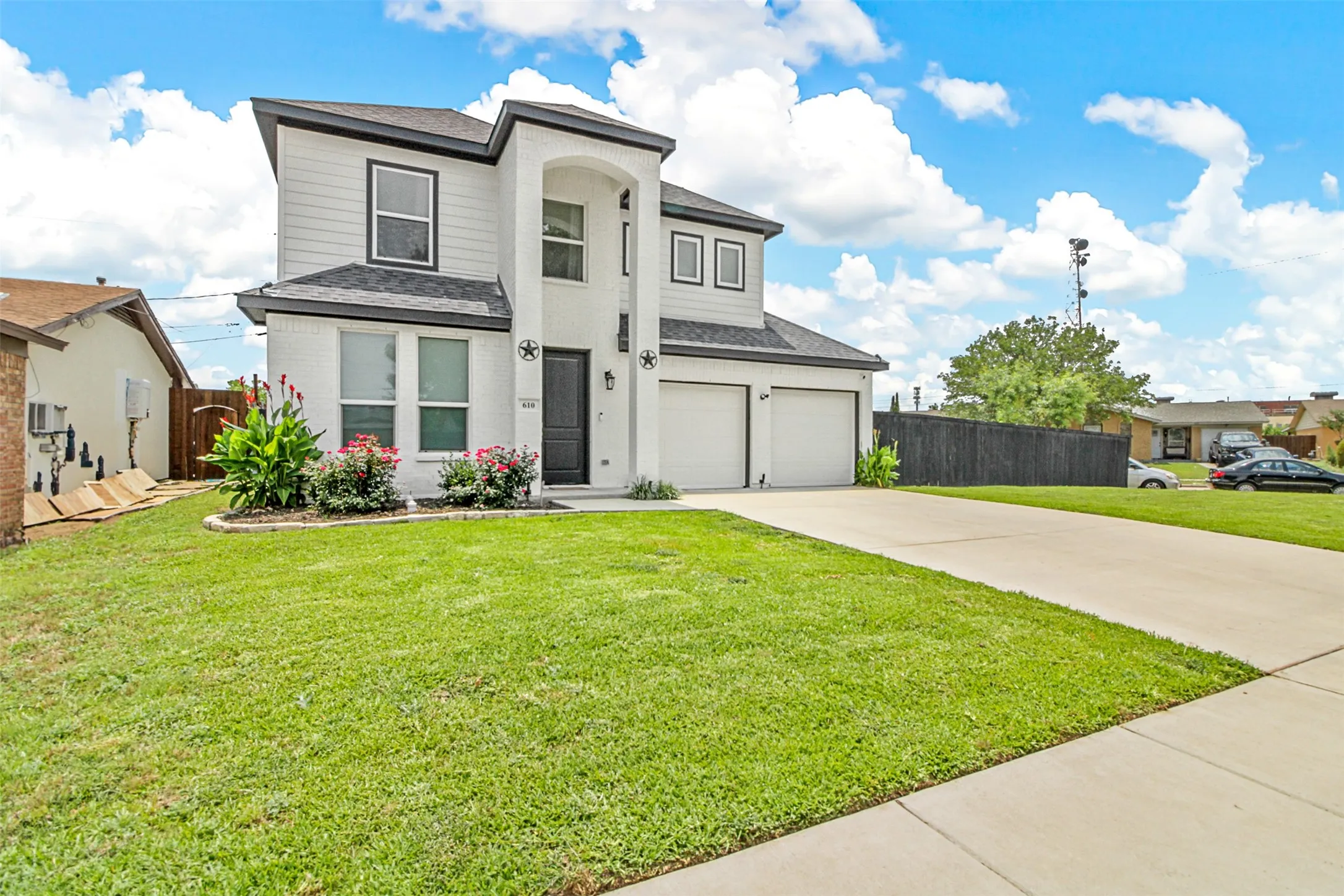 Two-story stucco and siding exterior, two-car garage, concrete driveway, and established front landscaping
