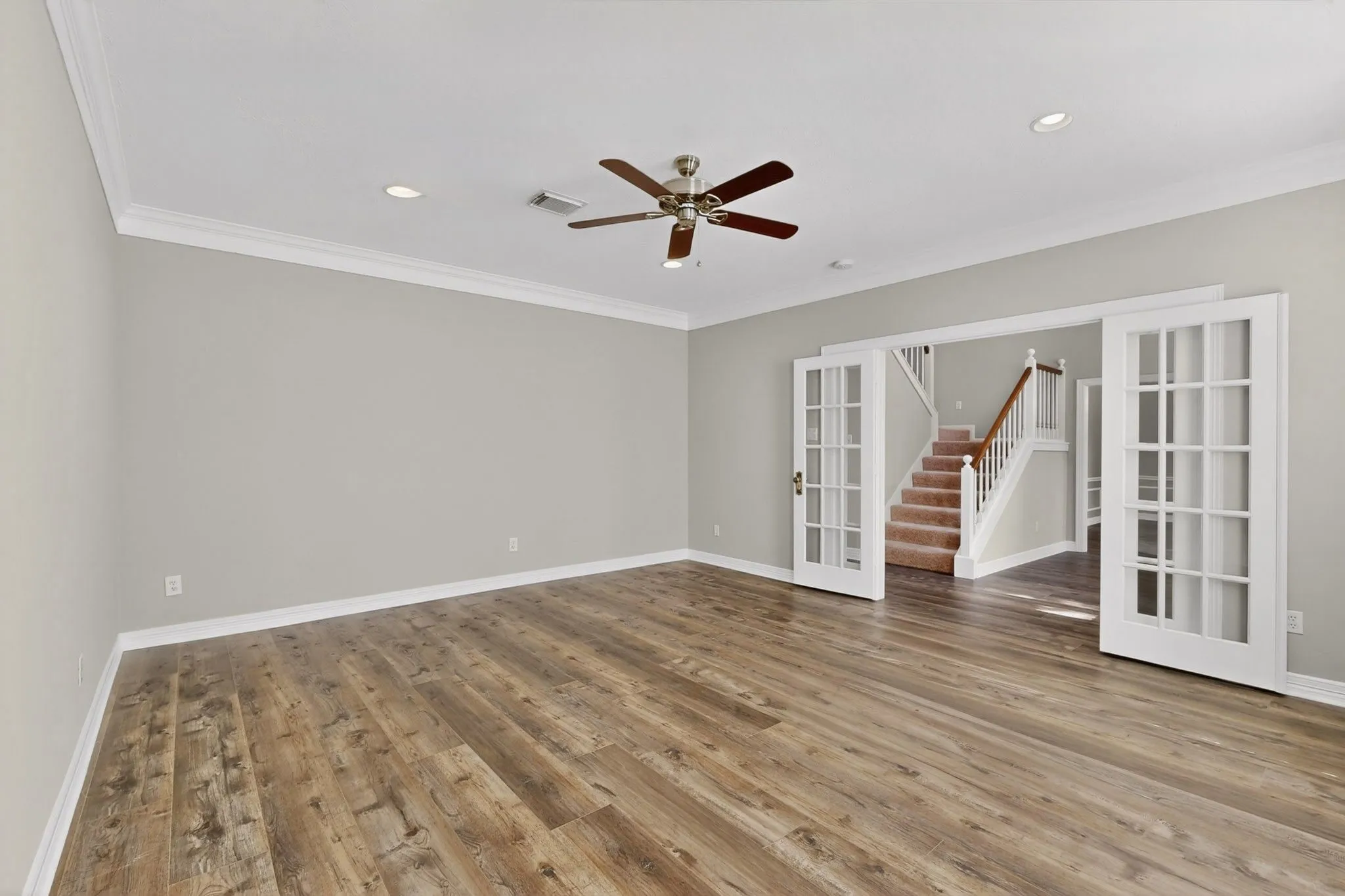 Wood-finish flooring, crown molding, recessed lighting, and a ceiling fan