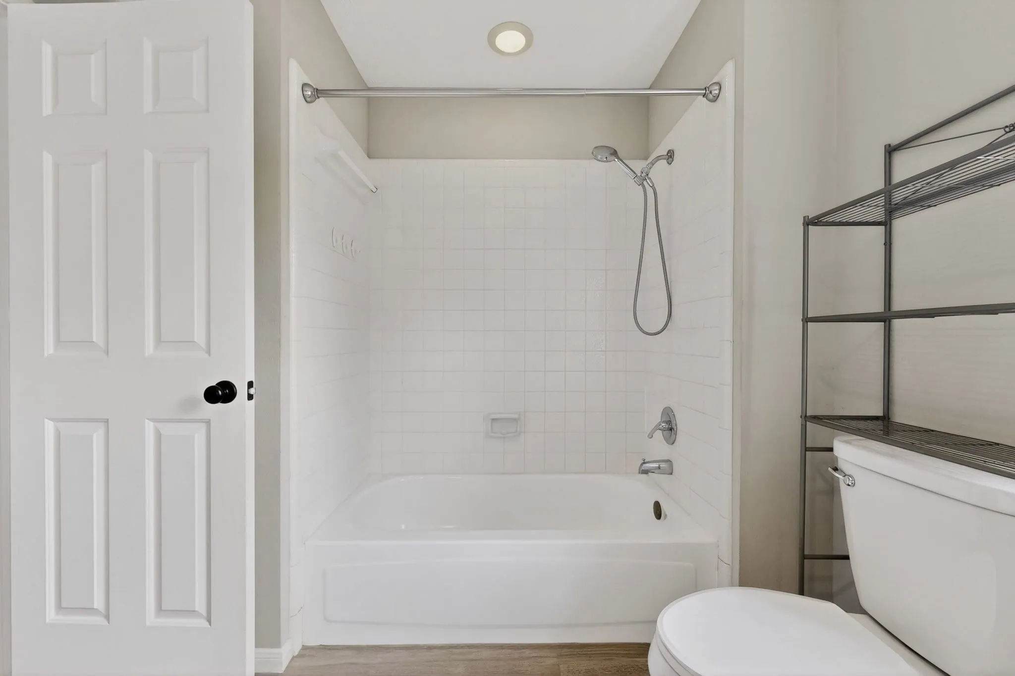Bathtub with white subway tile surround, chrome fixtures, and a shower curtain rod