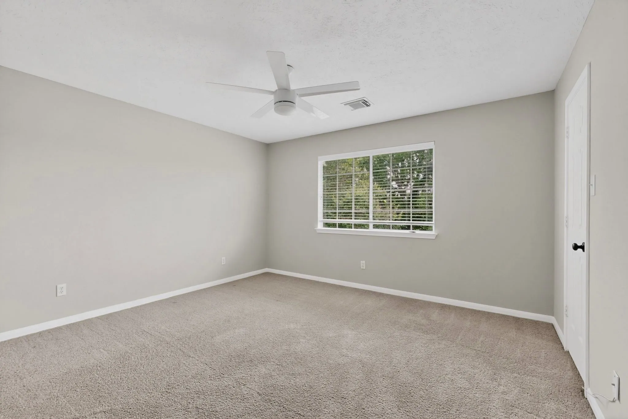 Wall-to-wall carpeting, neutral wall finishes, window with blinds, and ceiling fan
