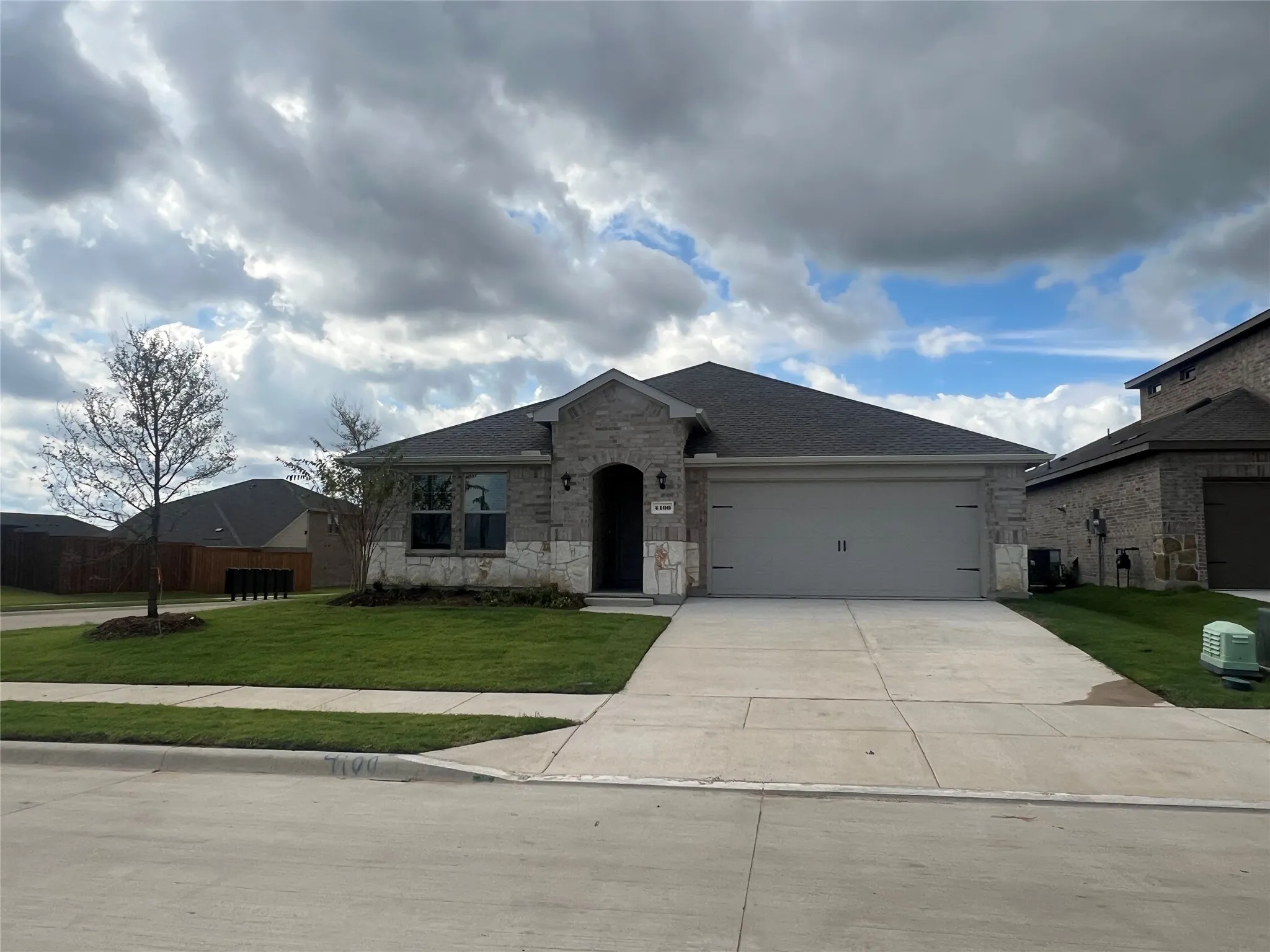 View of front of home with stone siding, driveway, an attached garage, and a shingled roof