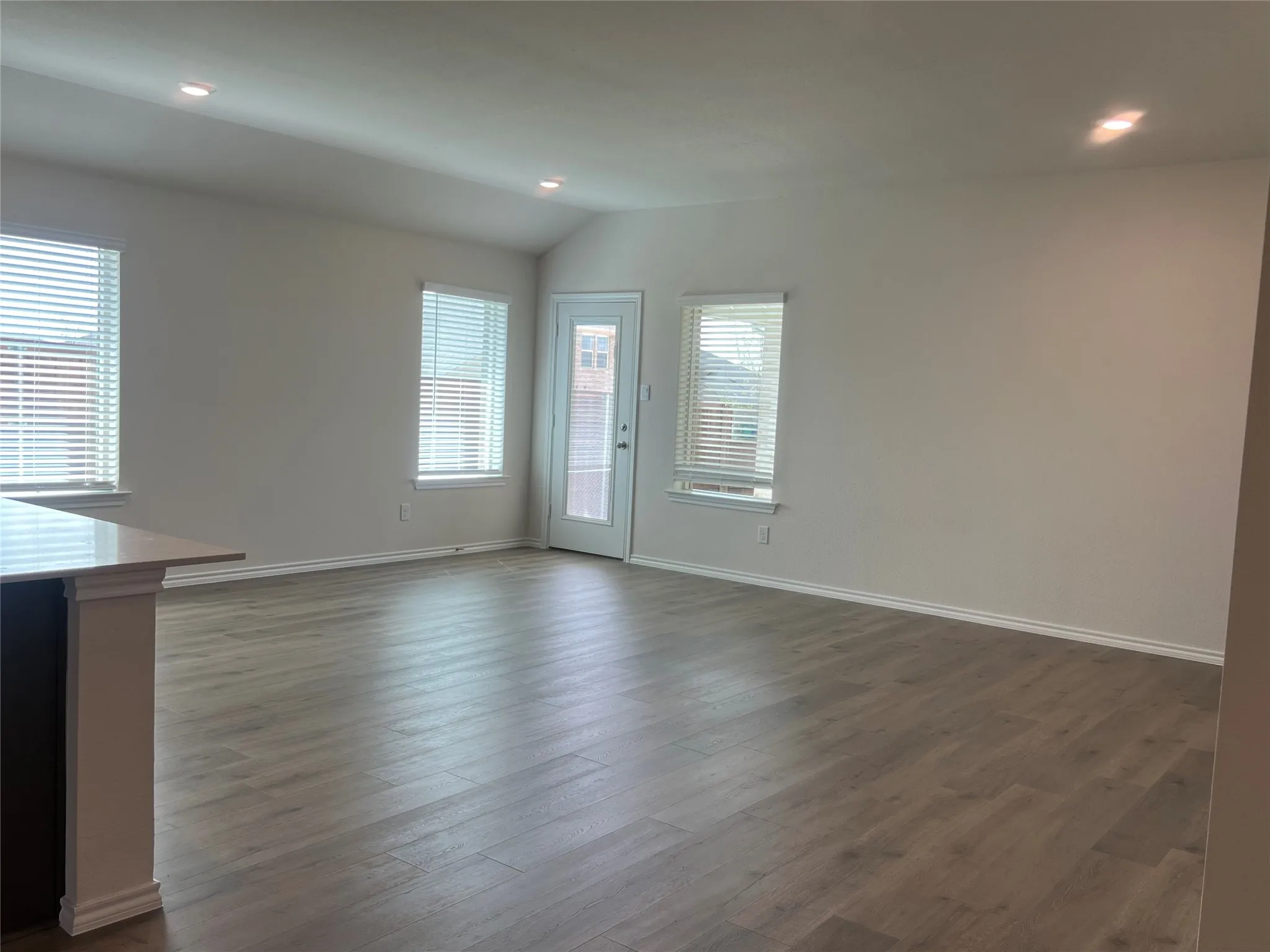 living room with dark vinyl finished floors, recessed lighting, and vaulted ceiling