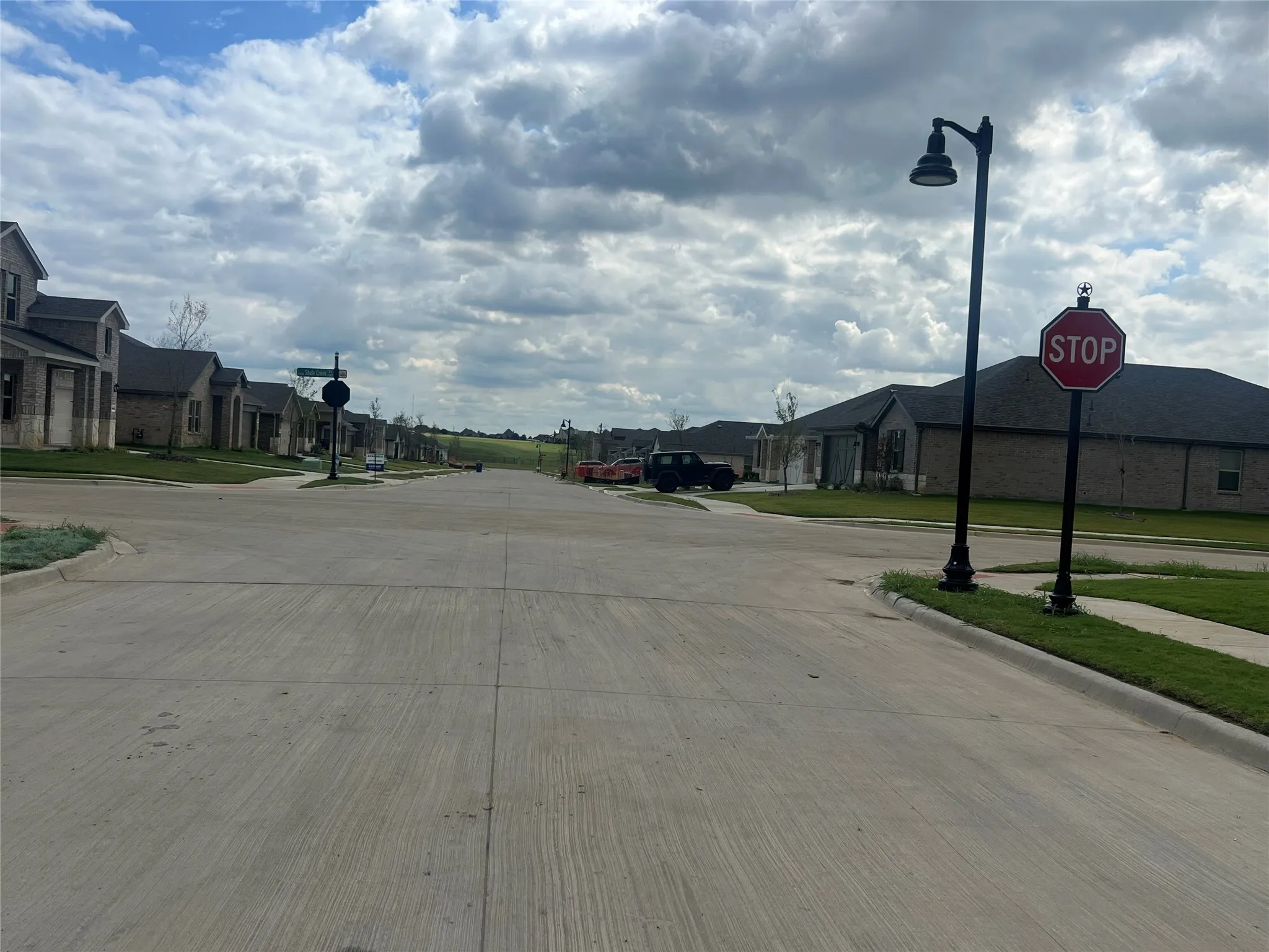View of street with traffic signs, sidewalks, curbs, a residential view, and street lights