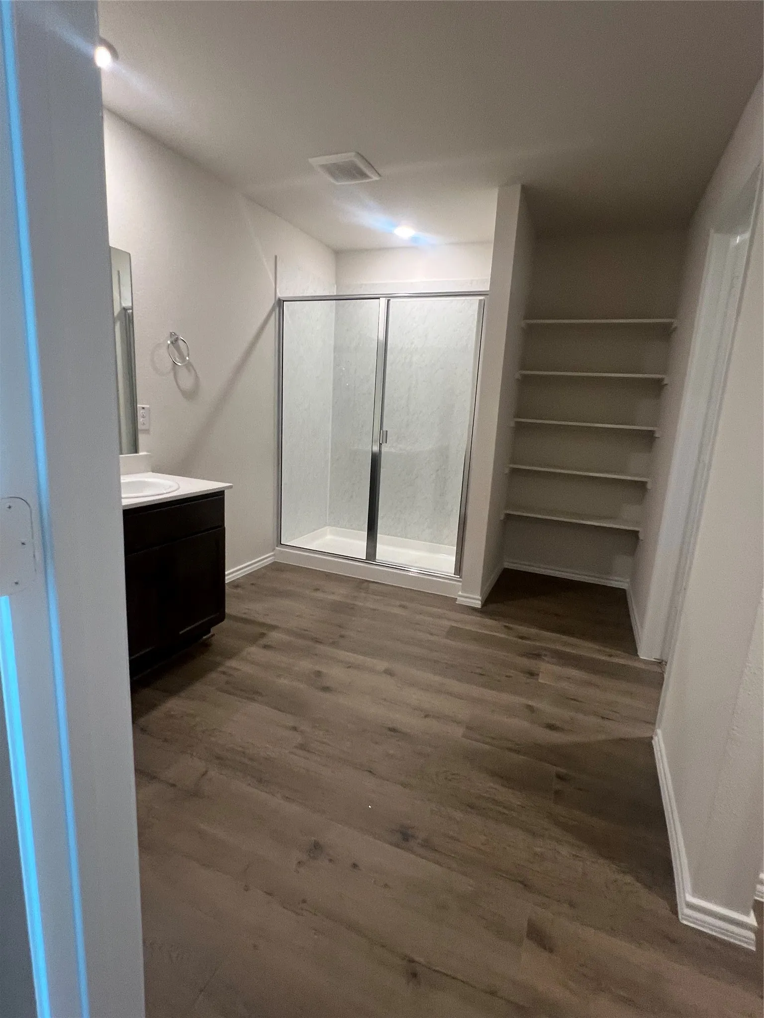 Full bath featuring vanity, a stall shower, dark wood-style floors, and a closet