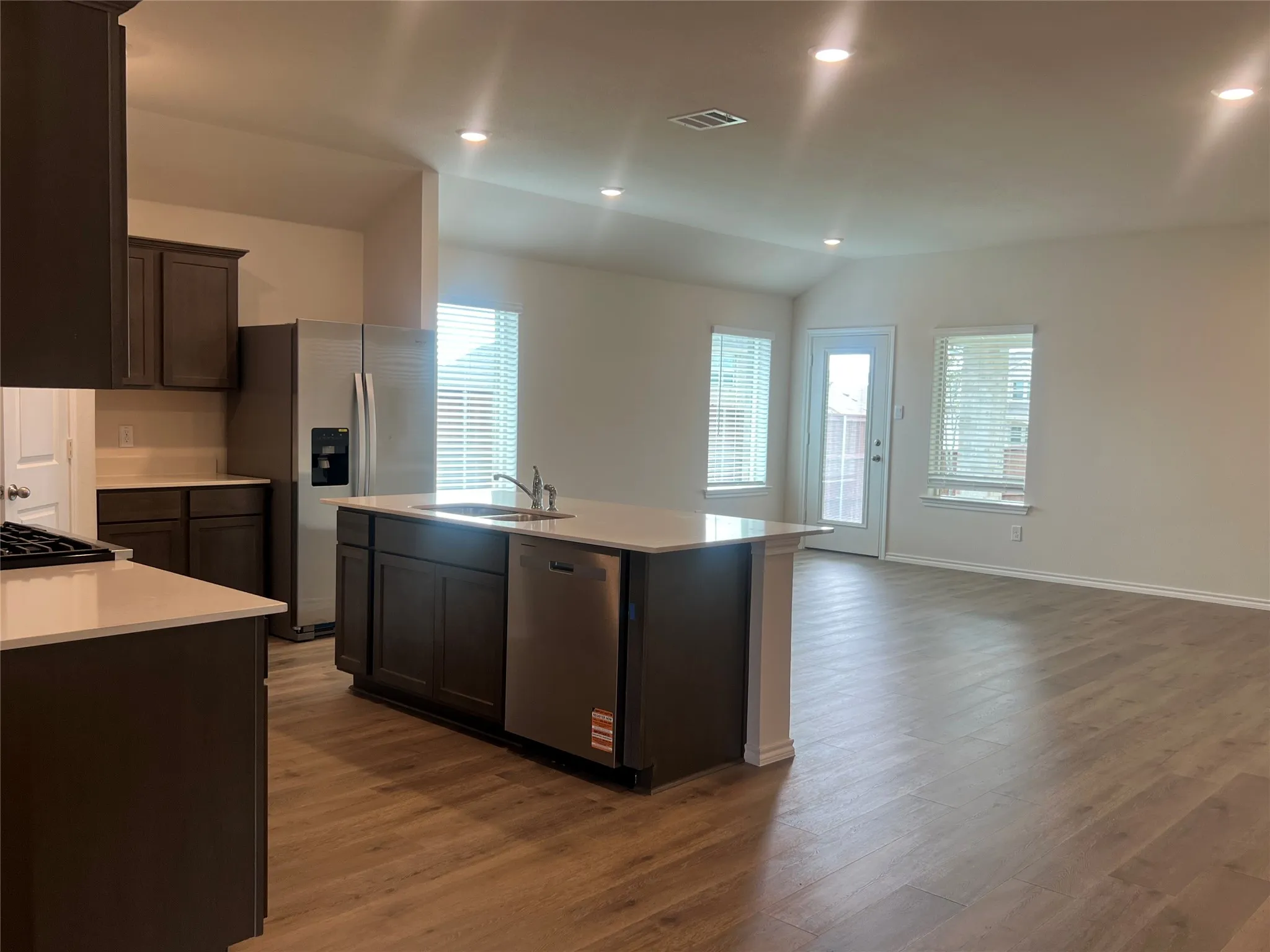 Kitchen with stainless steel appliances, recessed lighting, dark wood-type flooring, a center island with sink, and open floor plan