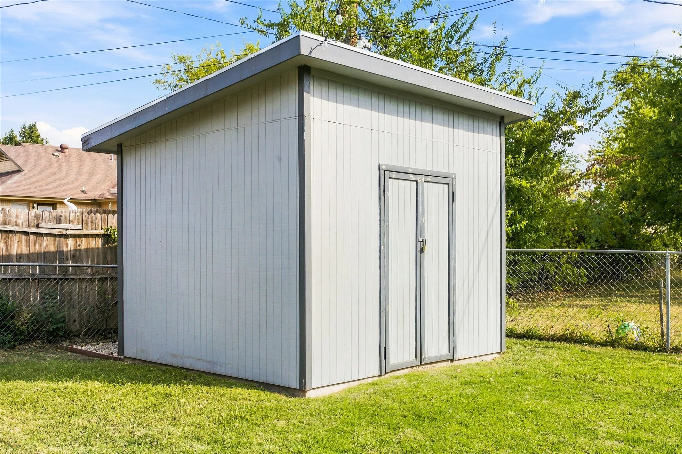 Standalone storage shed with a flat roof, dual entry doors, and a wood-paneled exterior