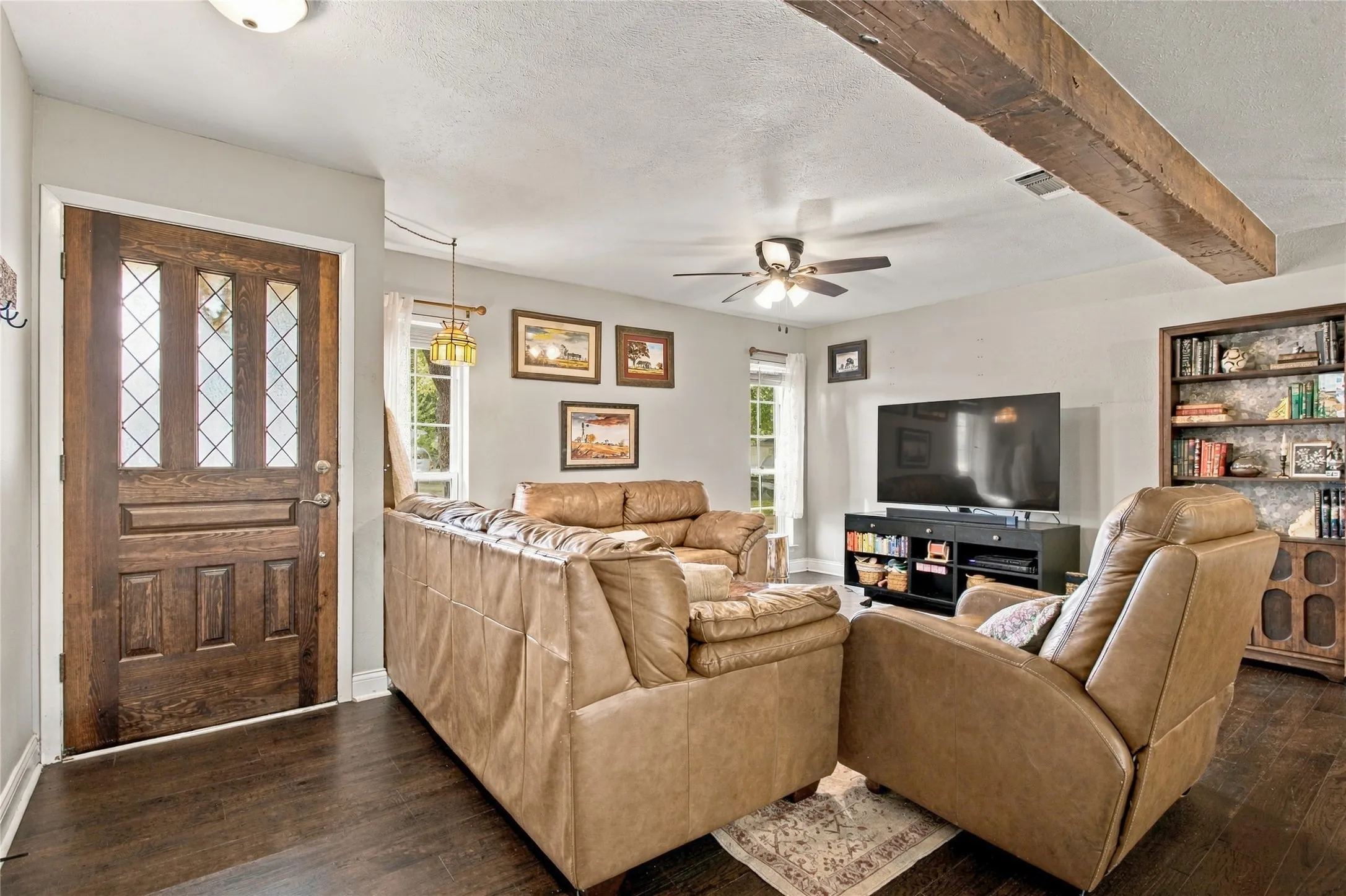 Wood-finish flooring, exposed ceiling beam, and a ceiling fan