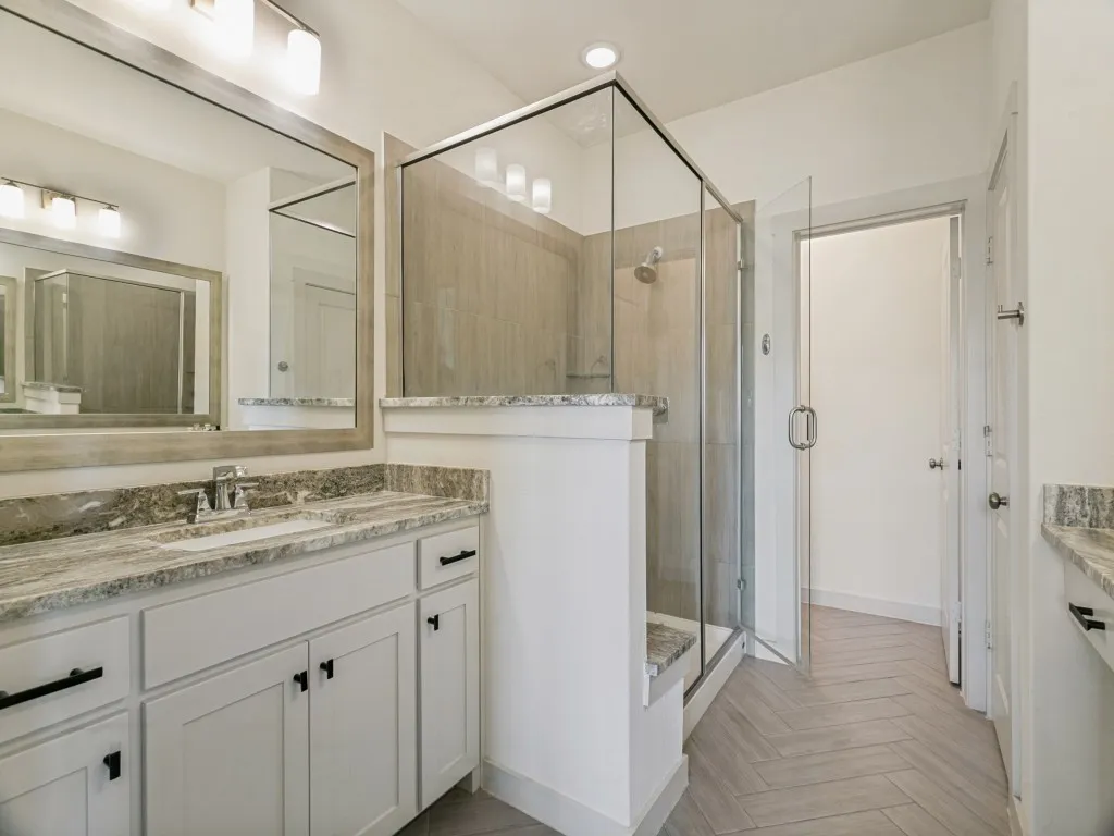 Dual vanity with undermount sinks, granite countertops, and white cabinetry