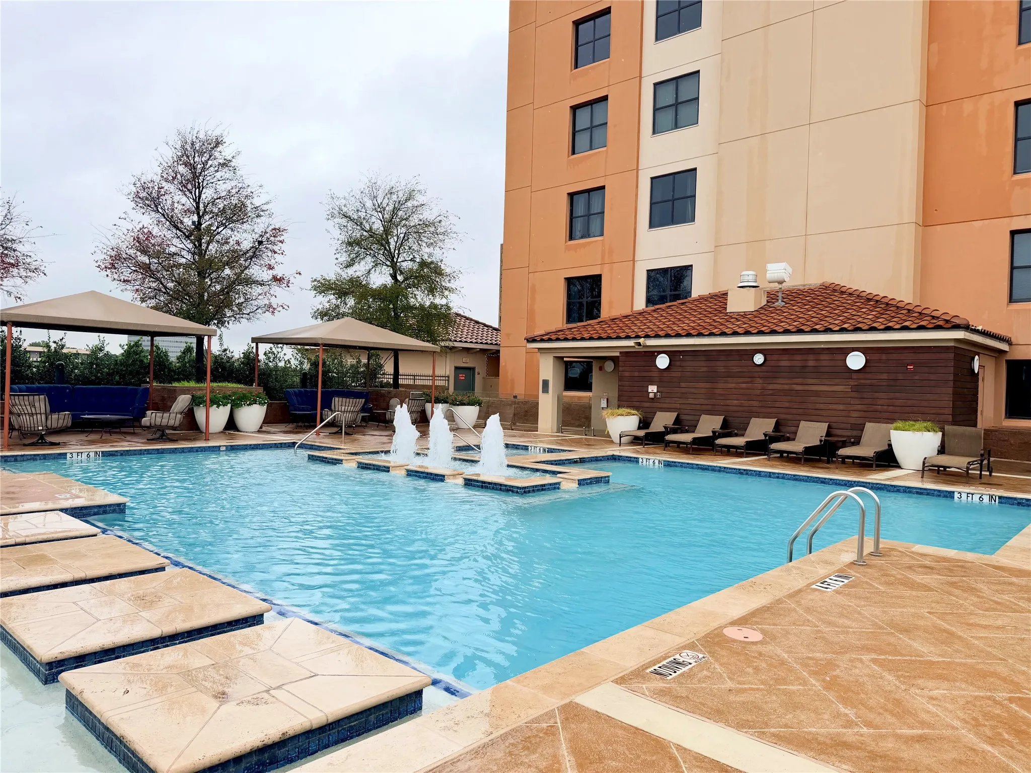 Outdoor swimming pool featuring water fountains, multiple shaded cabanas, and sun loungers