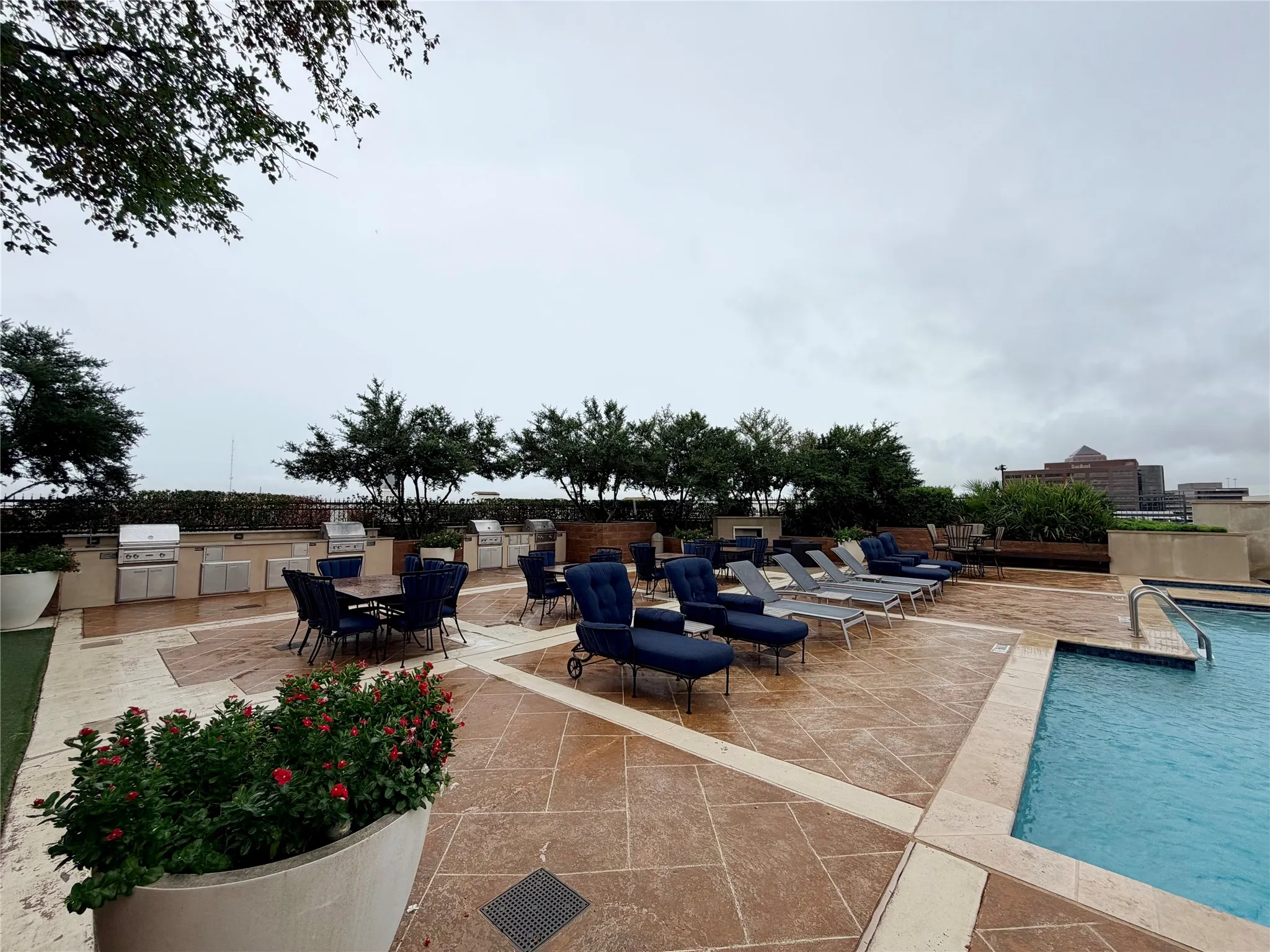 Rooftop amenity space featuring a swimming pool, multiple built-in grilling stations, extensive paver patio, and mature landscaping