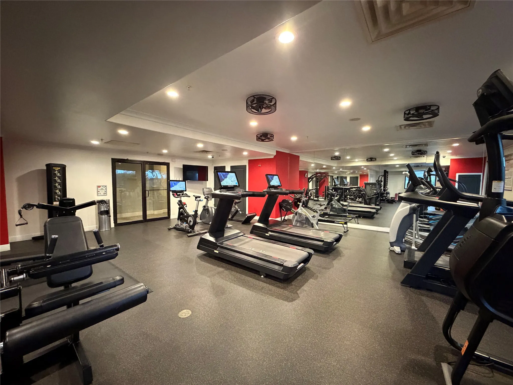 Fitness center featuring a rubberized floor, mirrored wall, recessed lighting, and modern exercise equipment