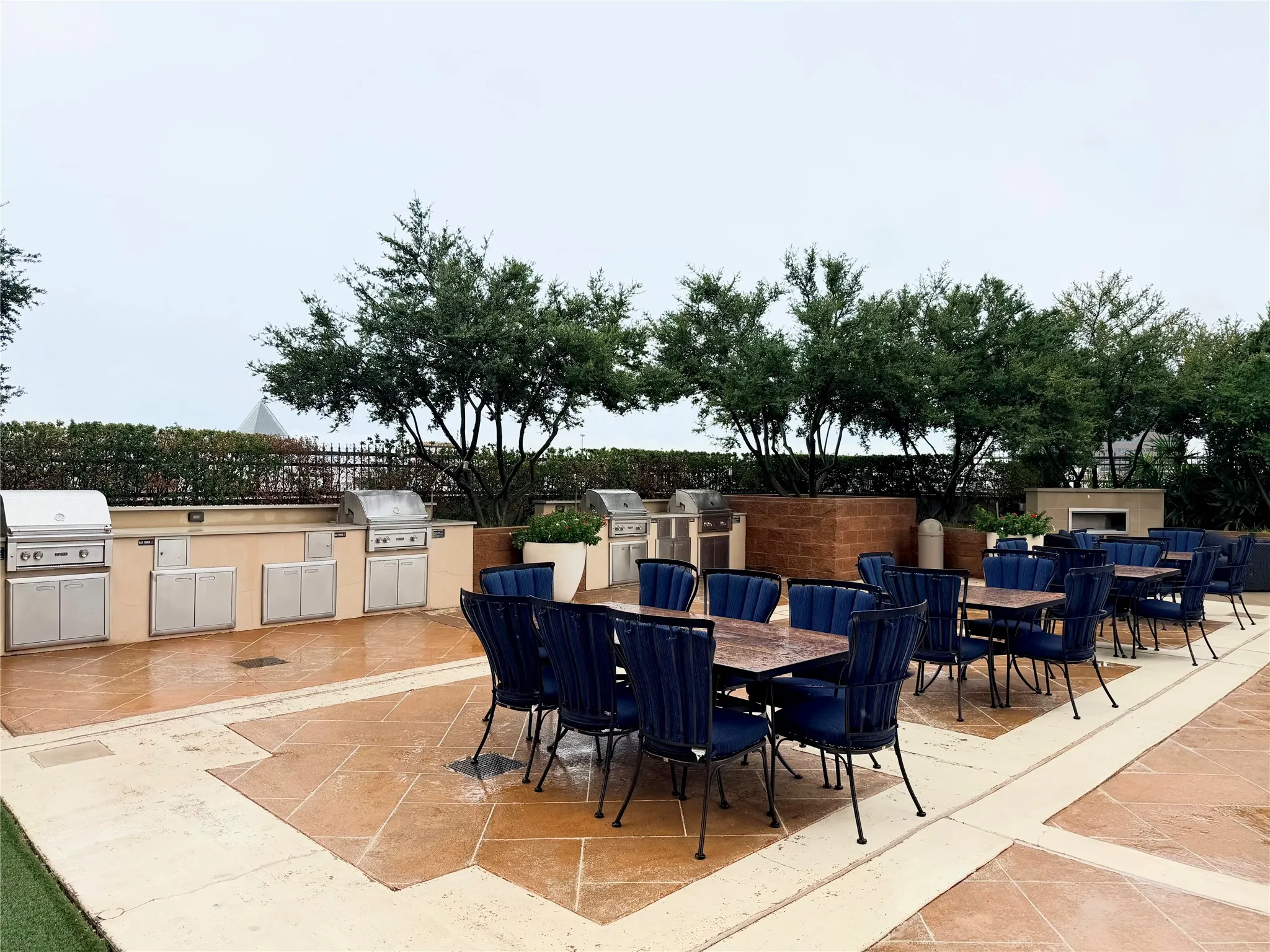 Outdoor kitchen area featuring multiple stainless steel grills, extensive counter space, and built-in cabinetry