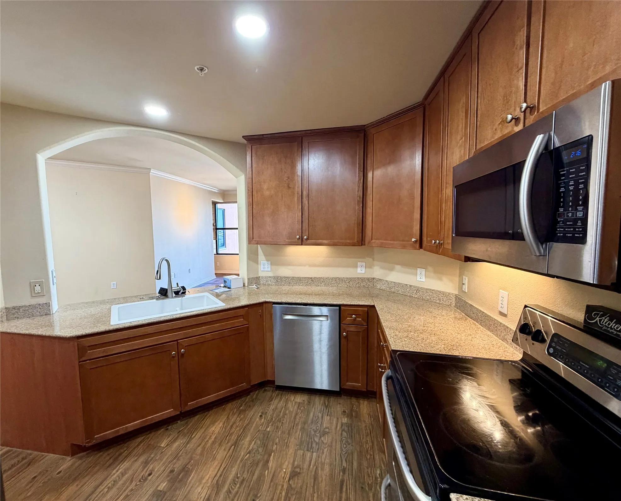 Kitchen featuring wood-finish cabinetry, stainless steel appliances, granite countertops, an undermount sink, and recessed lighting