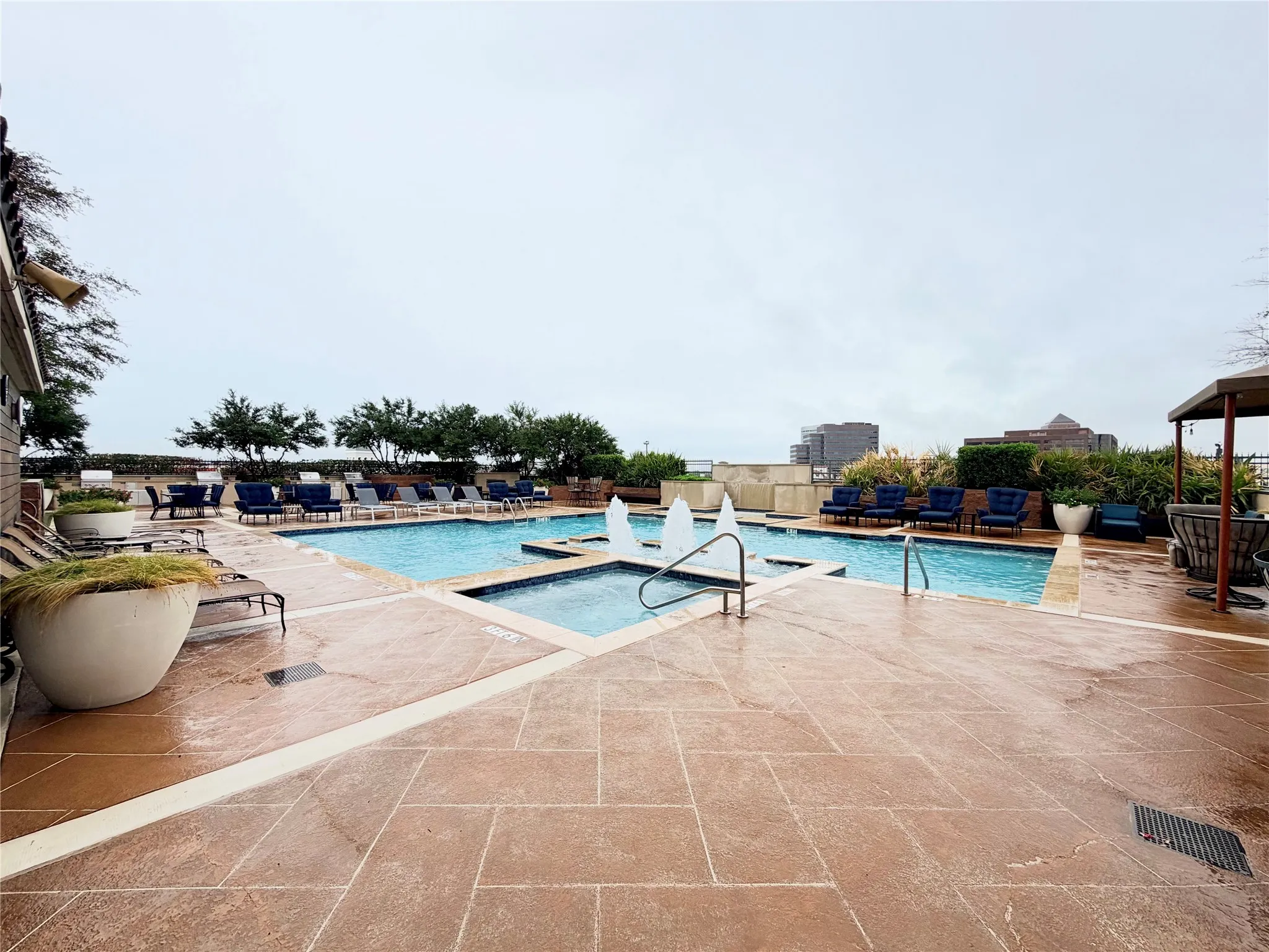 Expansive outdoor pool area featuring a rectangular pool, integrated spa, and a textured concrete deck