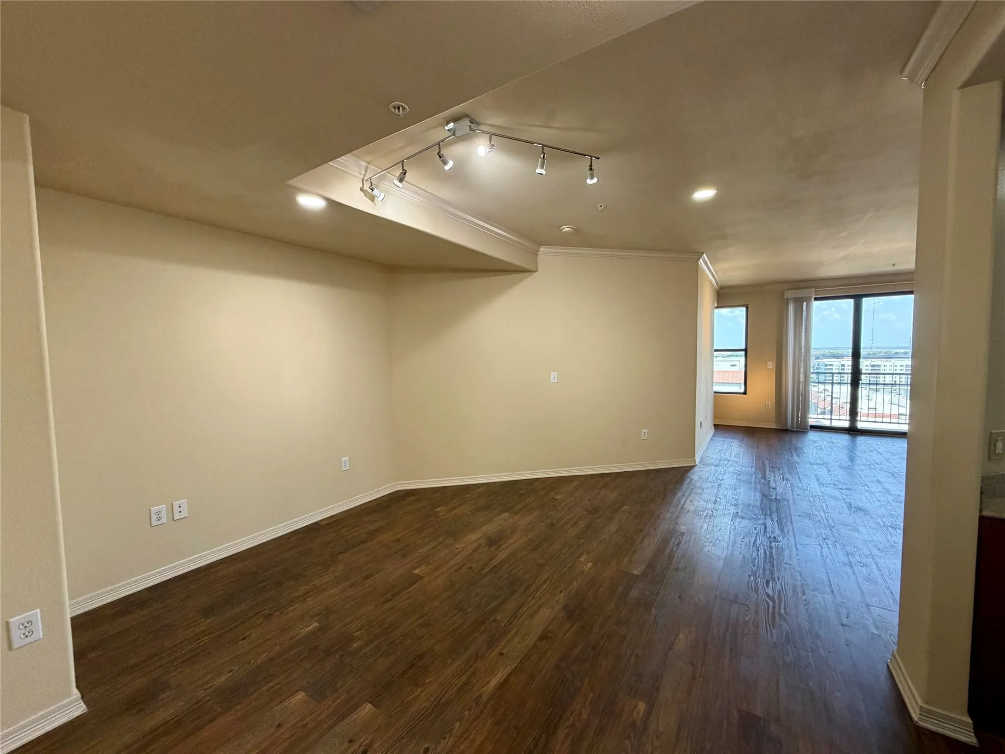 Expansive open-concept living area featuring wood-finish flooring, recessed lighting, and crown molding