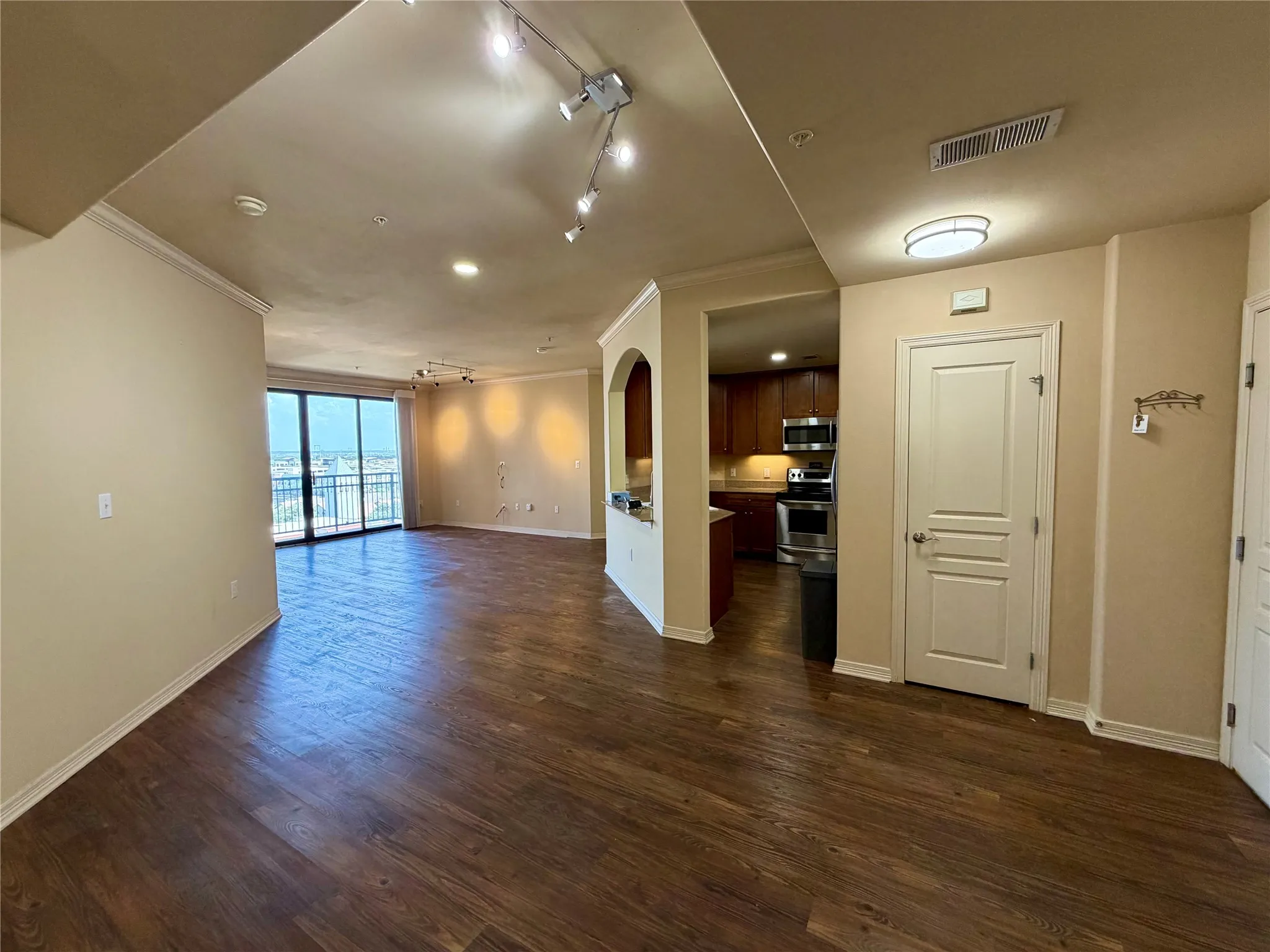 Expansive open-concept living area featuring wood-finish flooring, crown molding, and track lighting