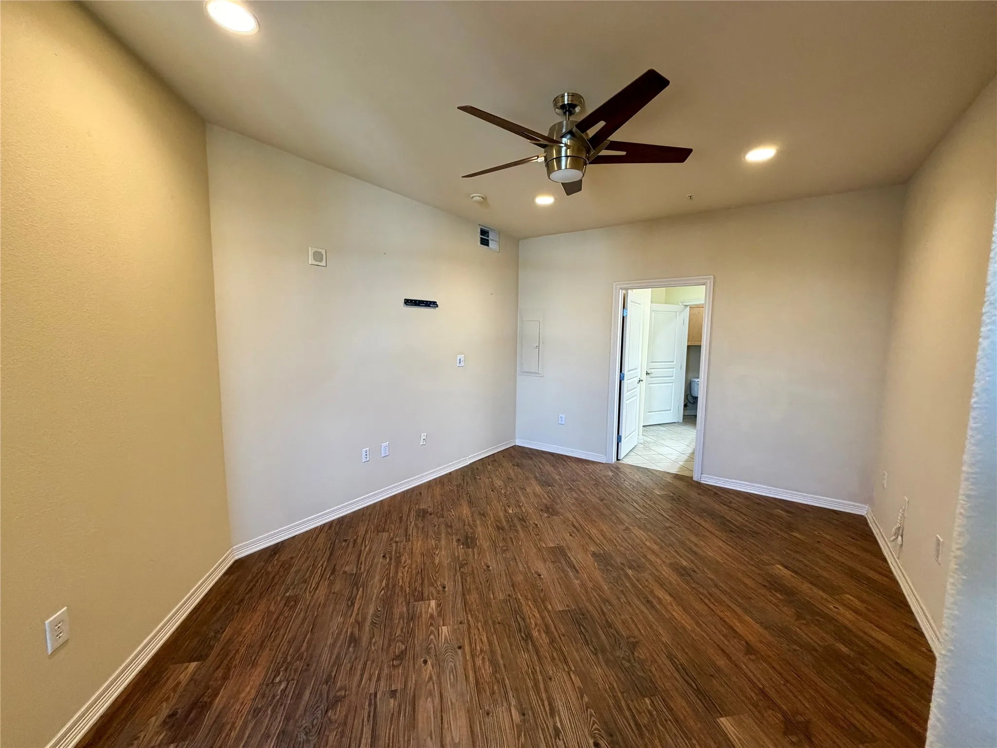 Wood-finish flooring, recessed lighting, ceiling fan, and white trim