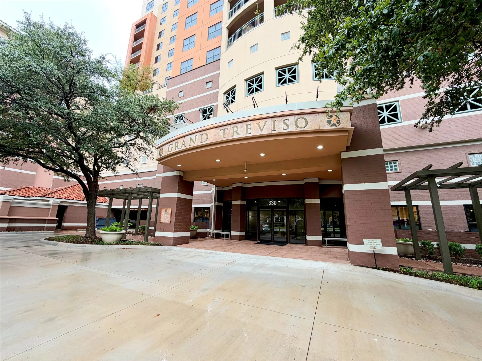 Arched entryway with a prominent sign, multiple windows with decorative grilles, and a curved drive