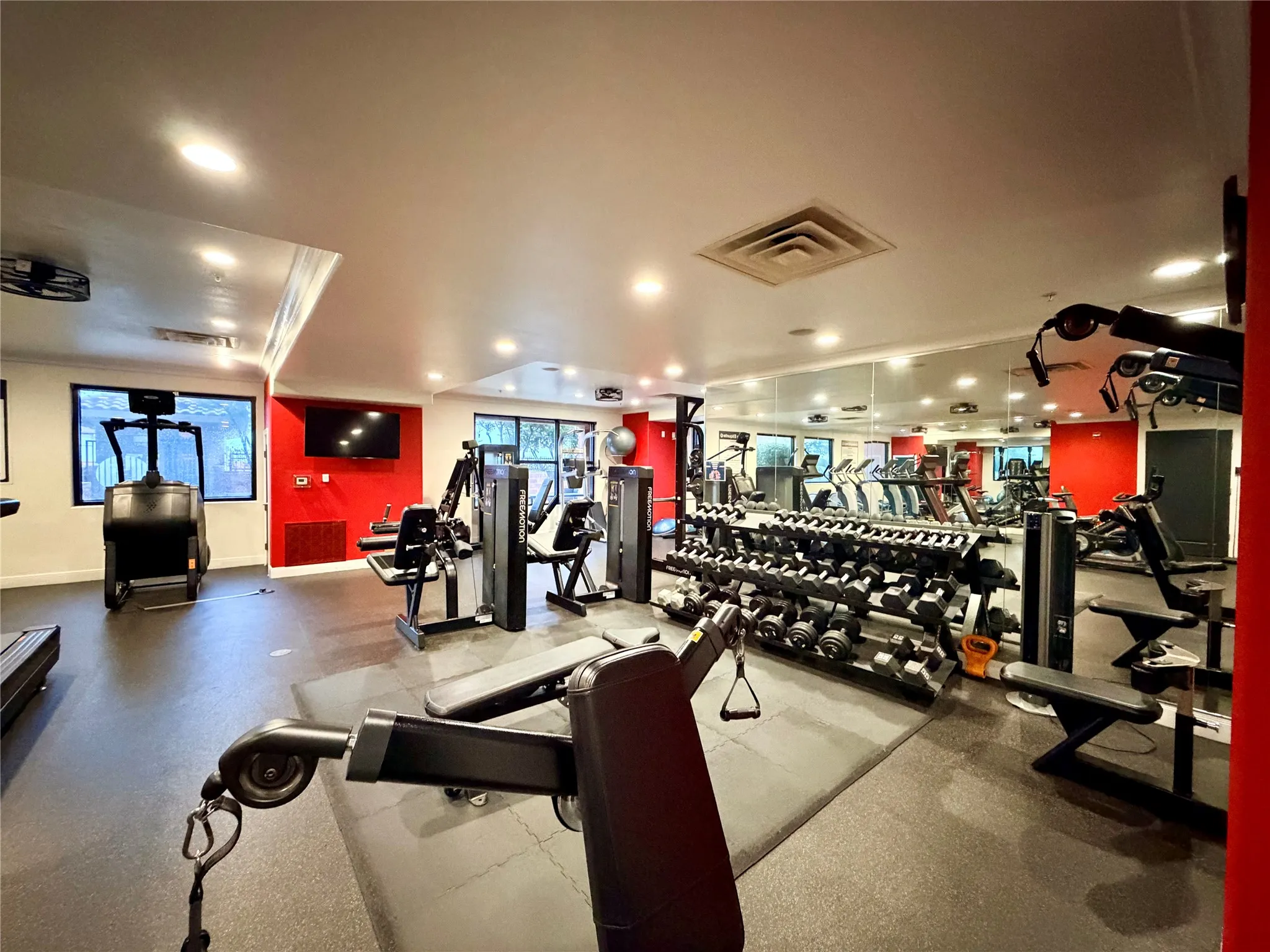 Fitness center with extensive mirrored wall, recessed lighting, and rubber flooring