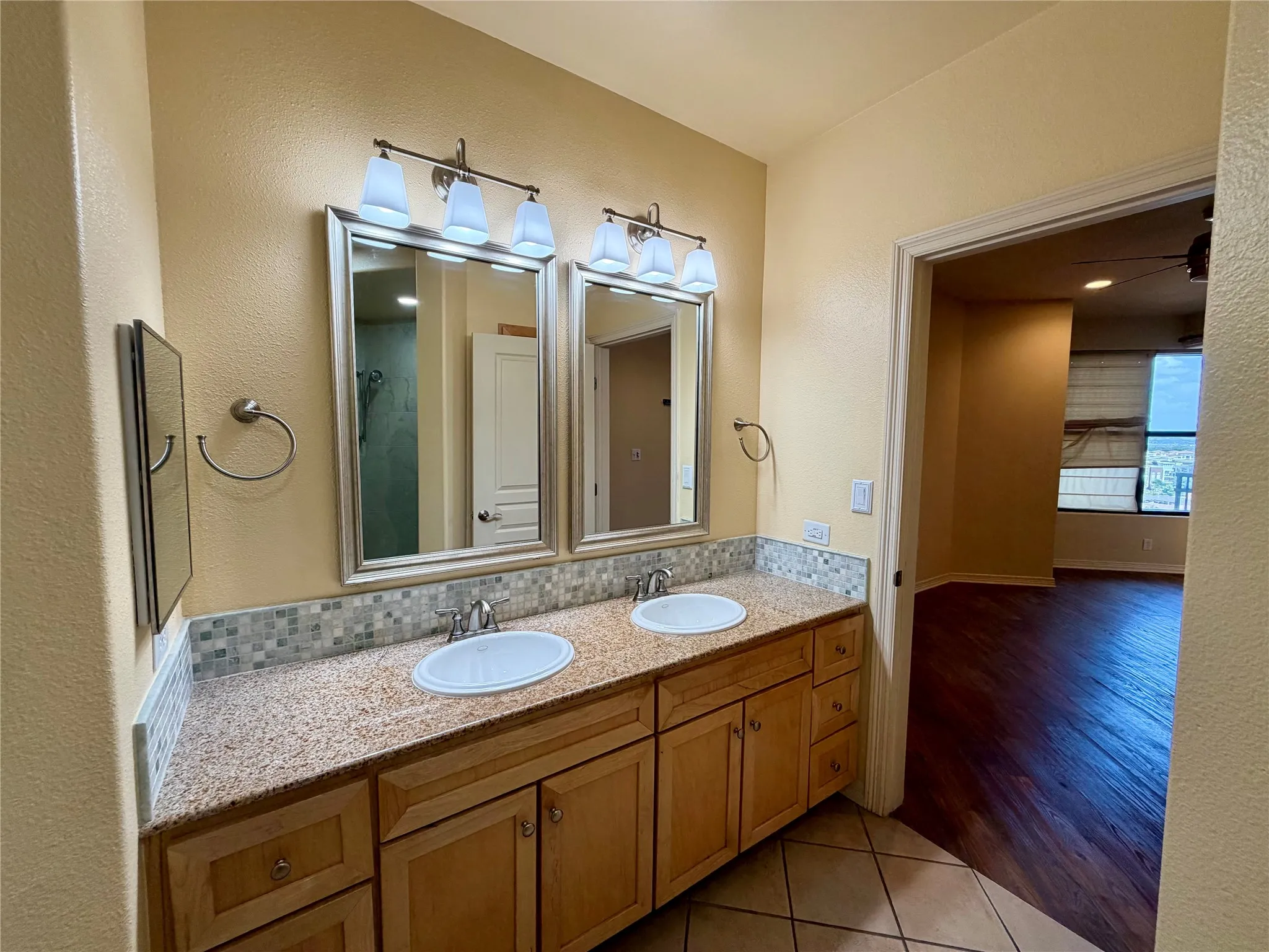 Dual vanity with granite countertops, mosaic tile backsplash, and individual framed mirrors