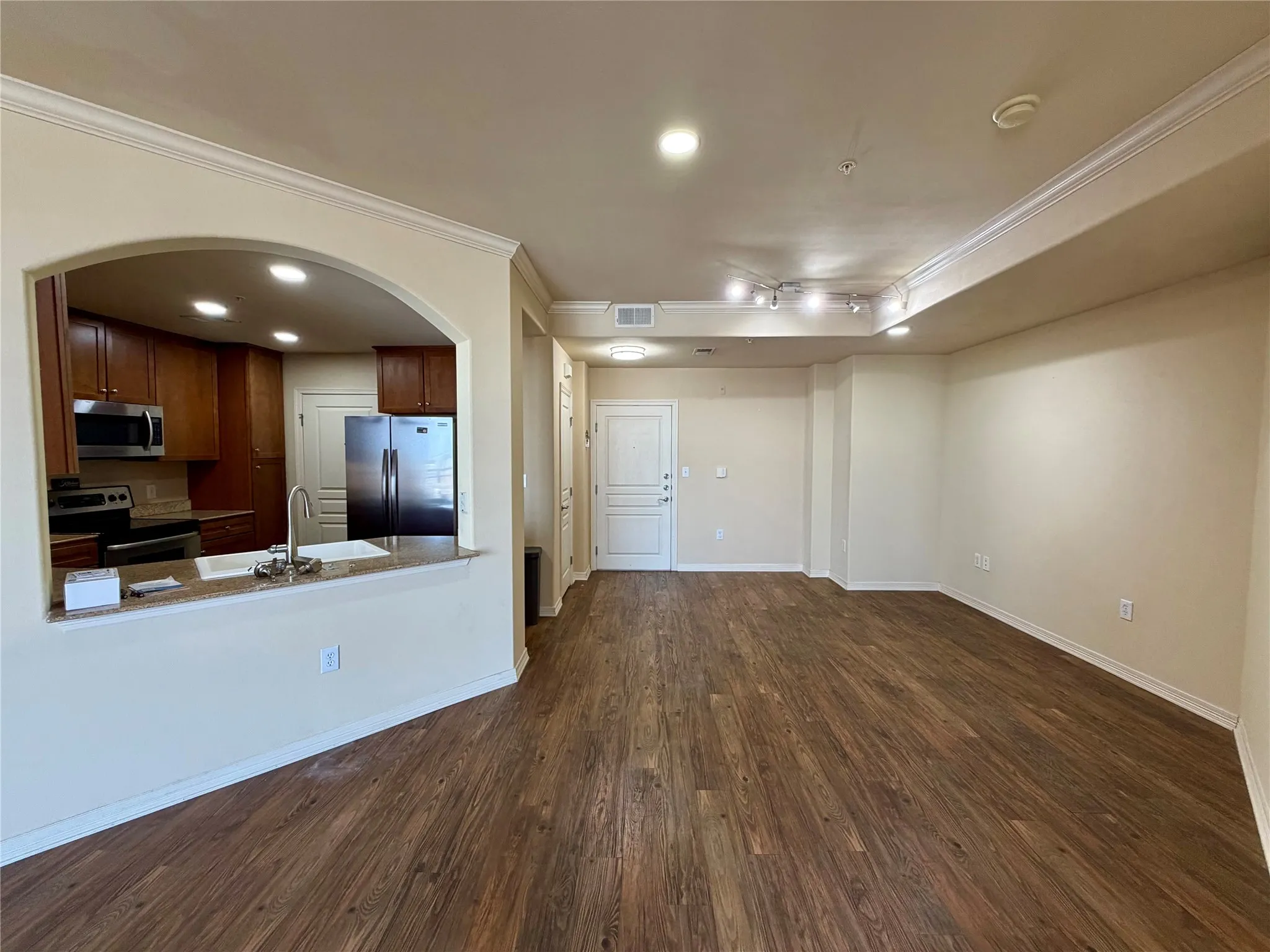 Spacious living area featuring wood-finish flooring, crown molding, and recessed lighting