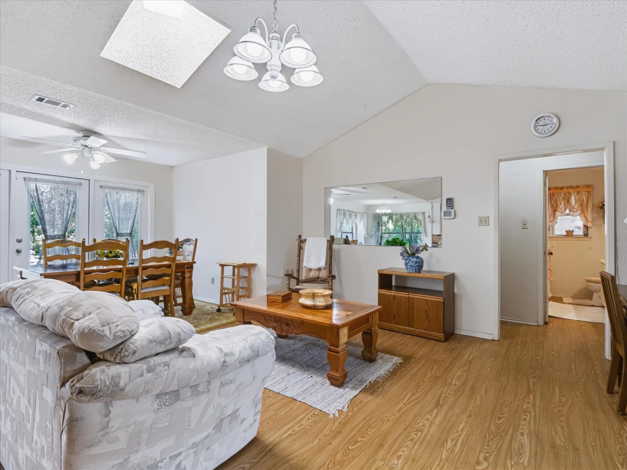 Vaulted ceilings, wood-finish flooring, skylight, and double patio doors