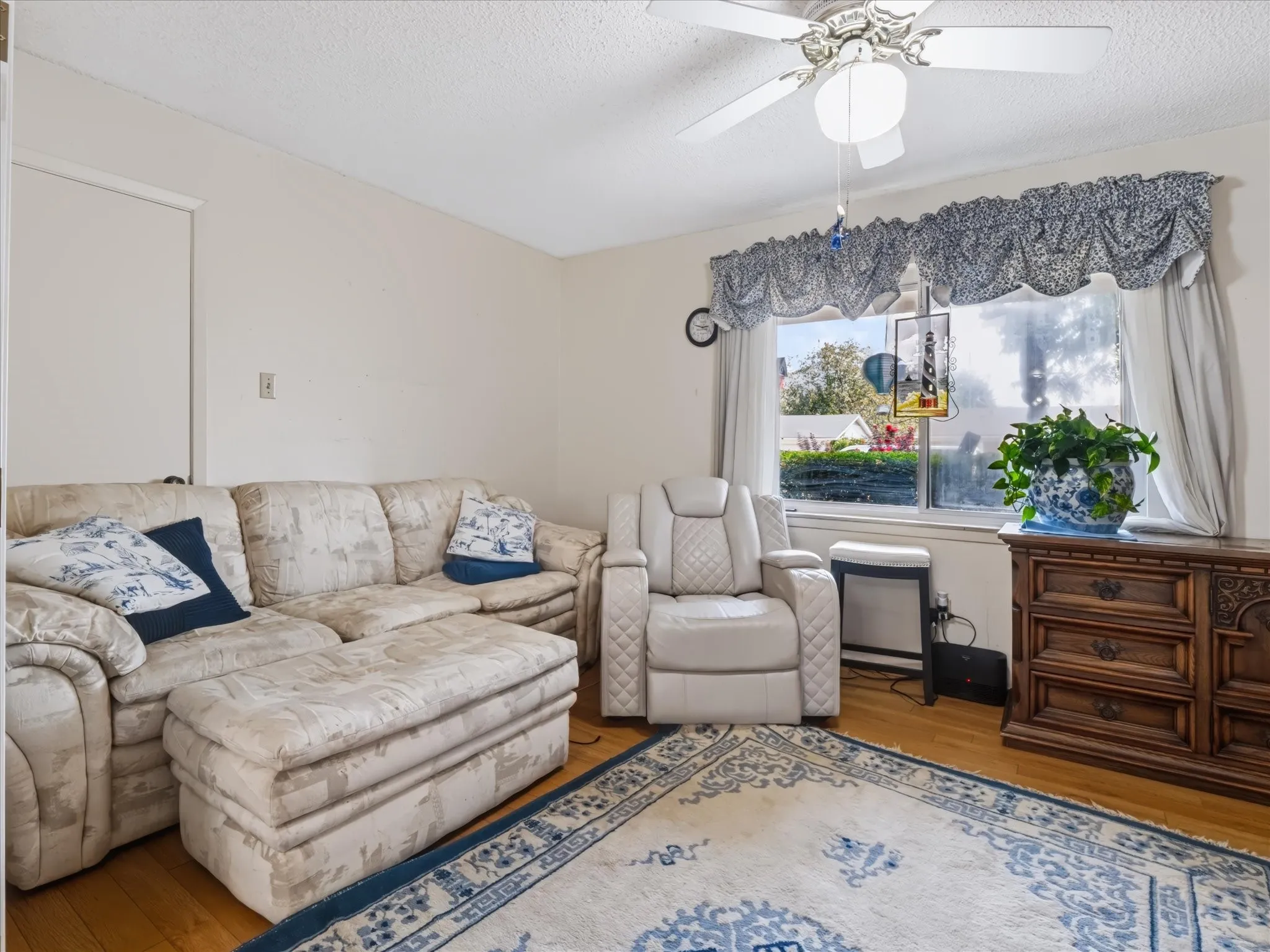 Wood-finish flooring, ceiling fan with integrated lighting, and a window offering natural illumination