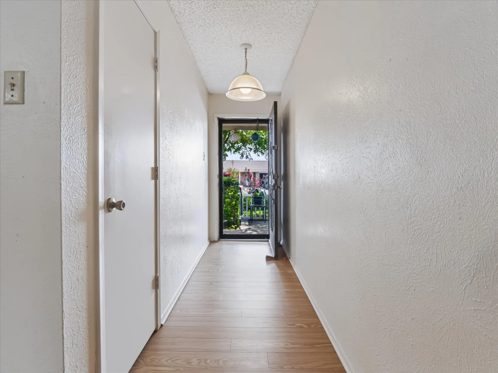 Hallway featuring wood-finish flooring, a semi-flush mount ceiling light, and a door with a security screen