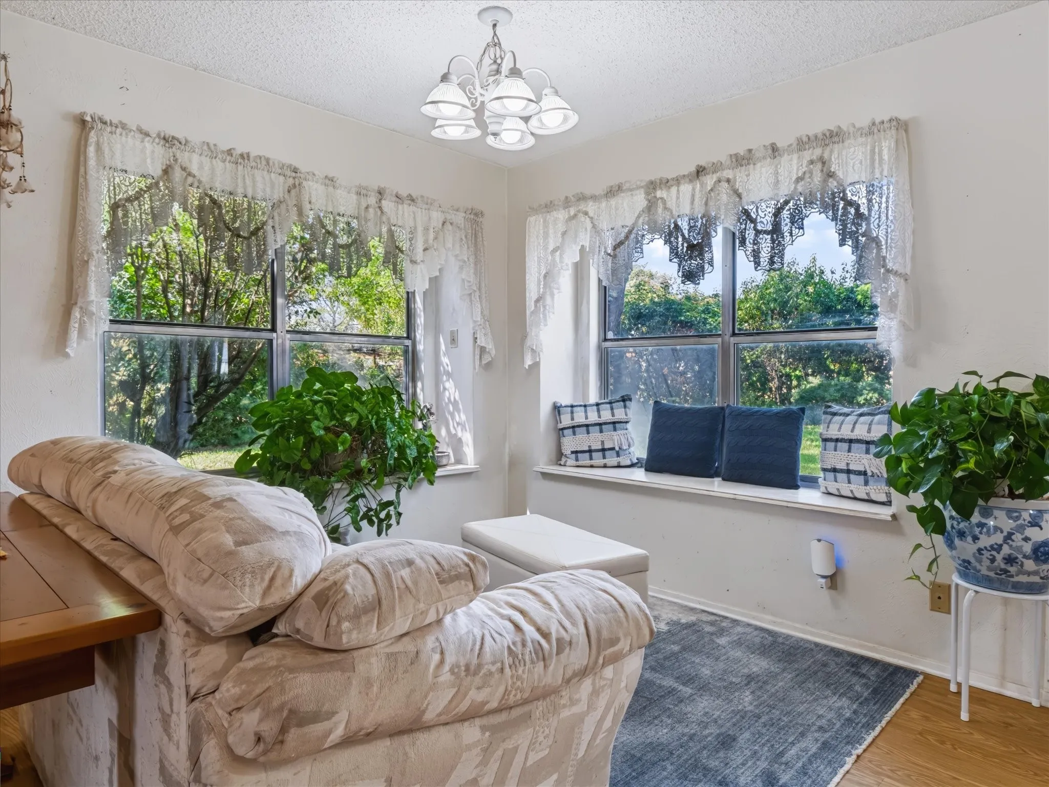 Corner window seating area with a white window ledge, a multi-light chandelier, and multiple paneled windows