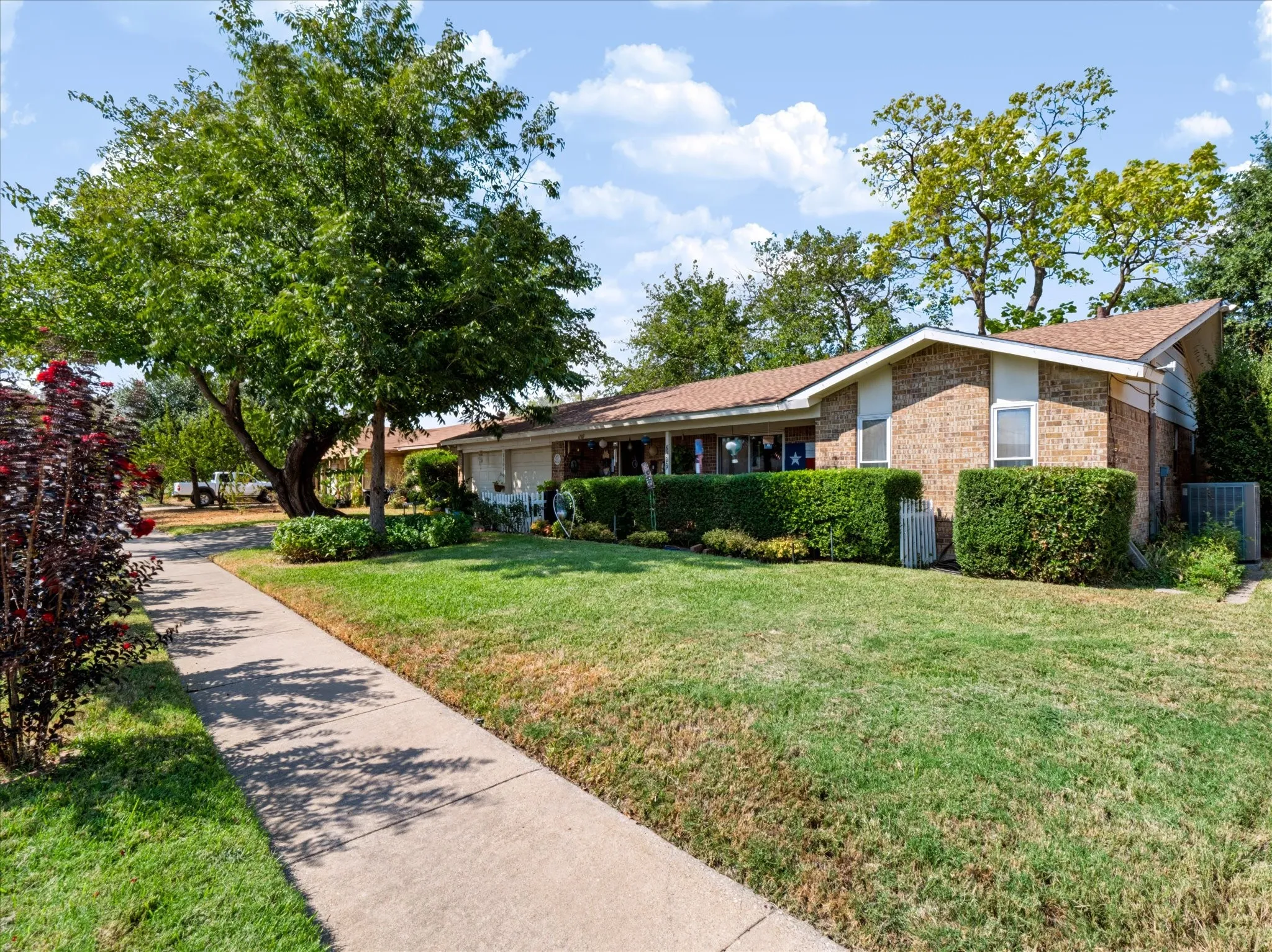 Brick exterior with white trim, covered front entry, and mature landscaping