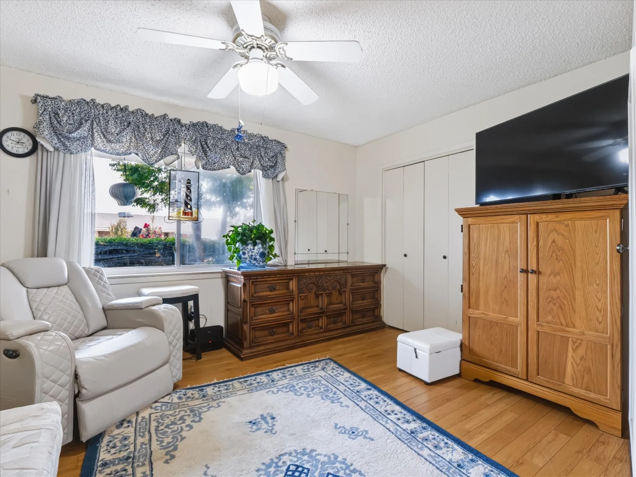 Vaulted ceiling with a ceiling fan, window with privacy coverings, and wood-finish flooring
