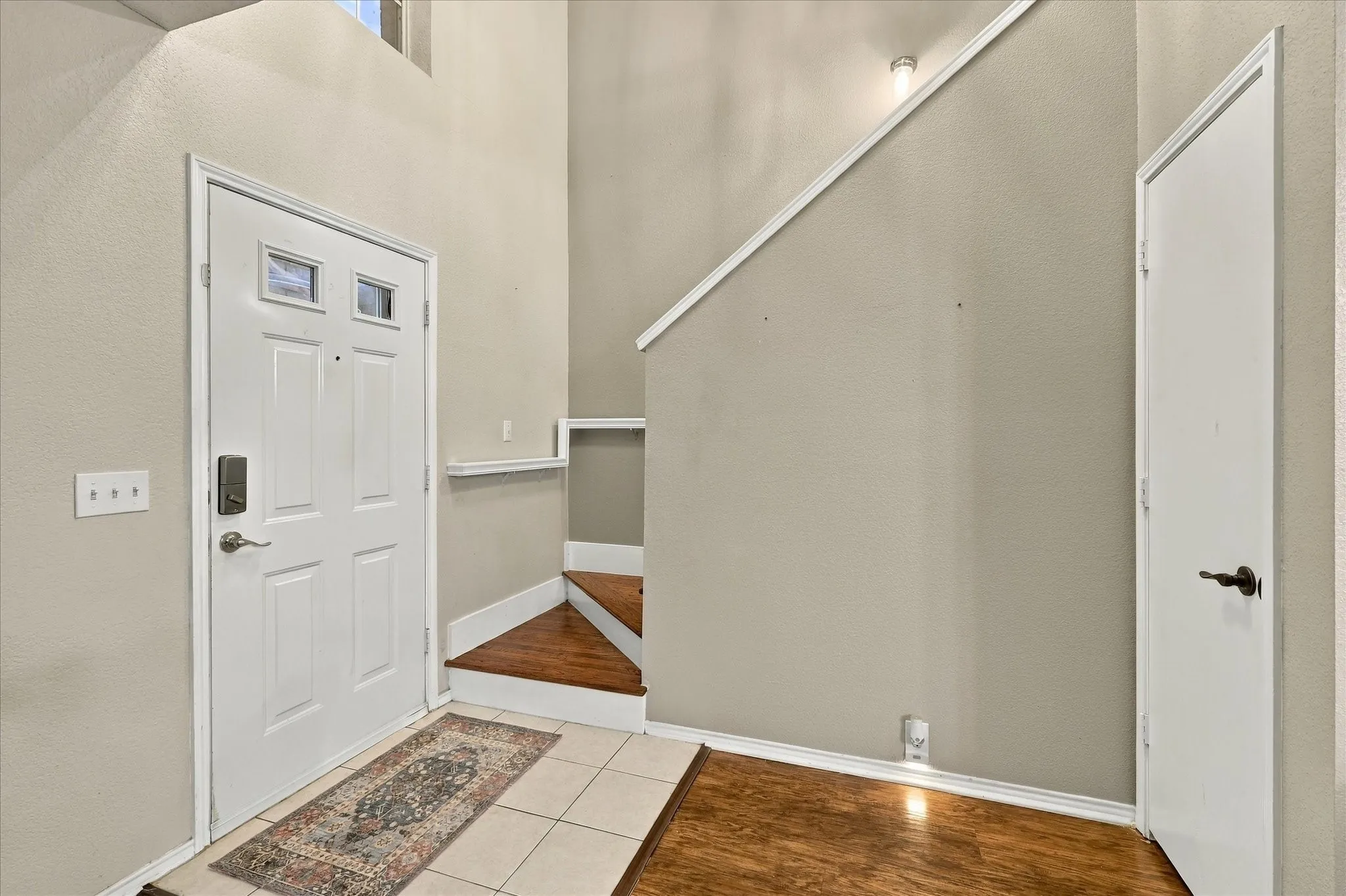 Entryway featuring a white paneled door with integrated window panels, smart lock hardware, and tile flooring