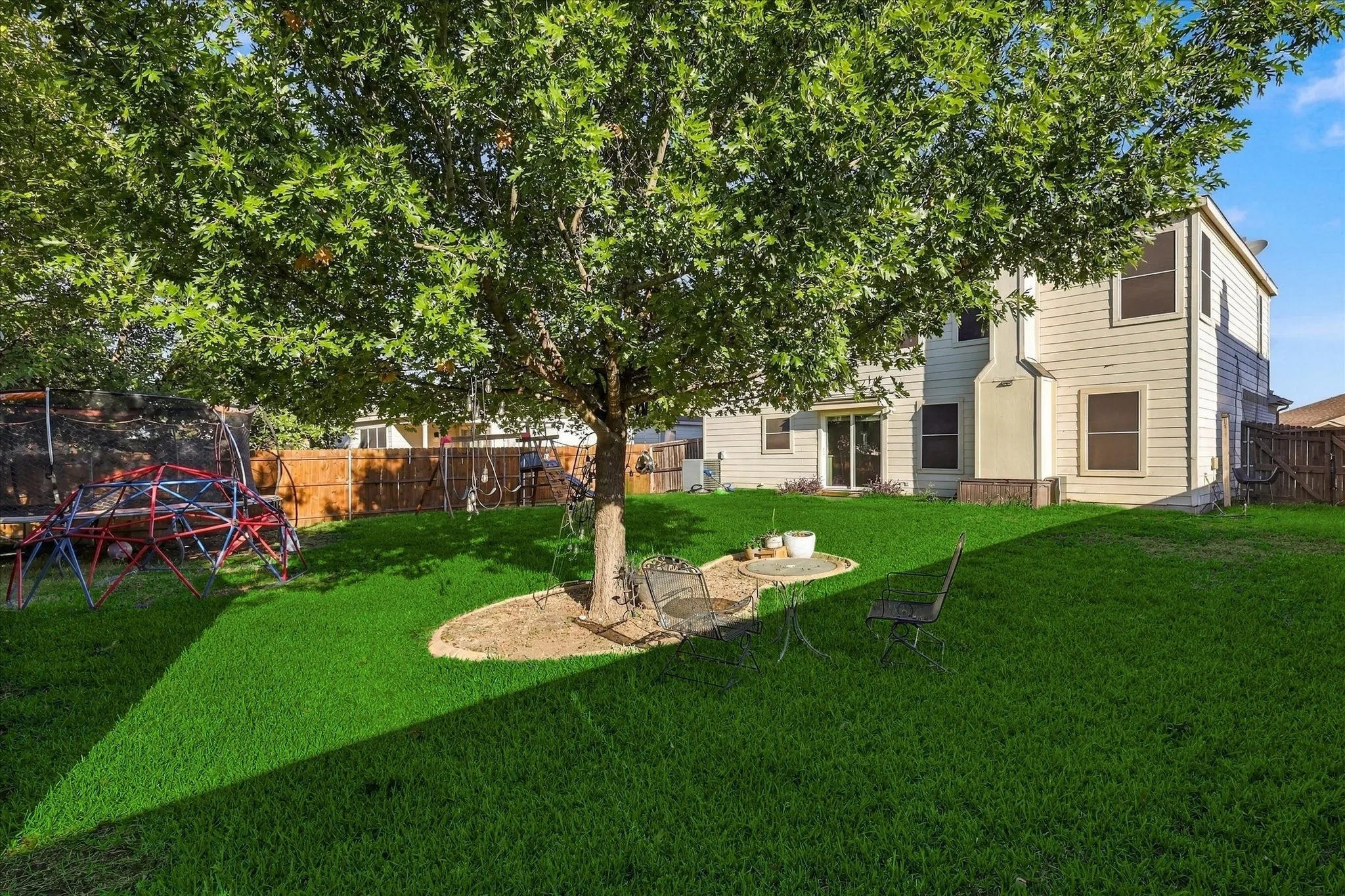 Expansive green lawn, mature shade tree, privacy fencing, and a two-story exterior