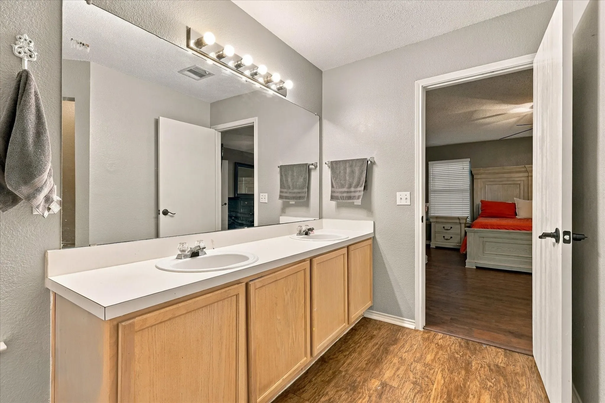 Dual vanity with integral sinks, expansive mirror, and wood-finish flooring
