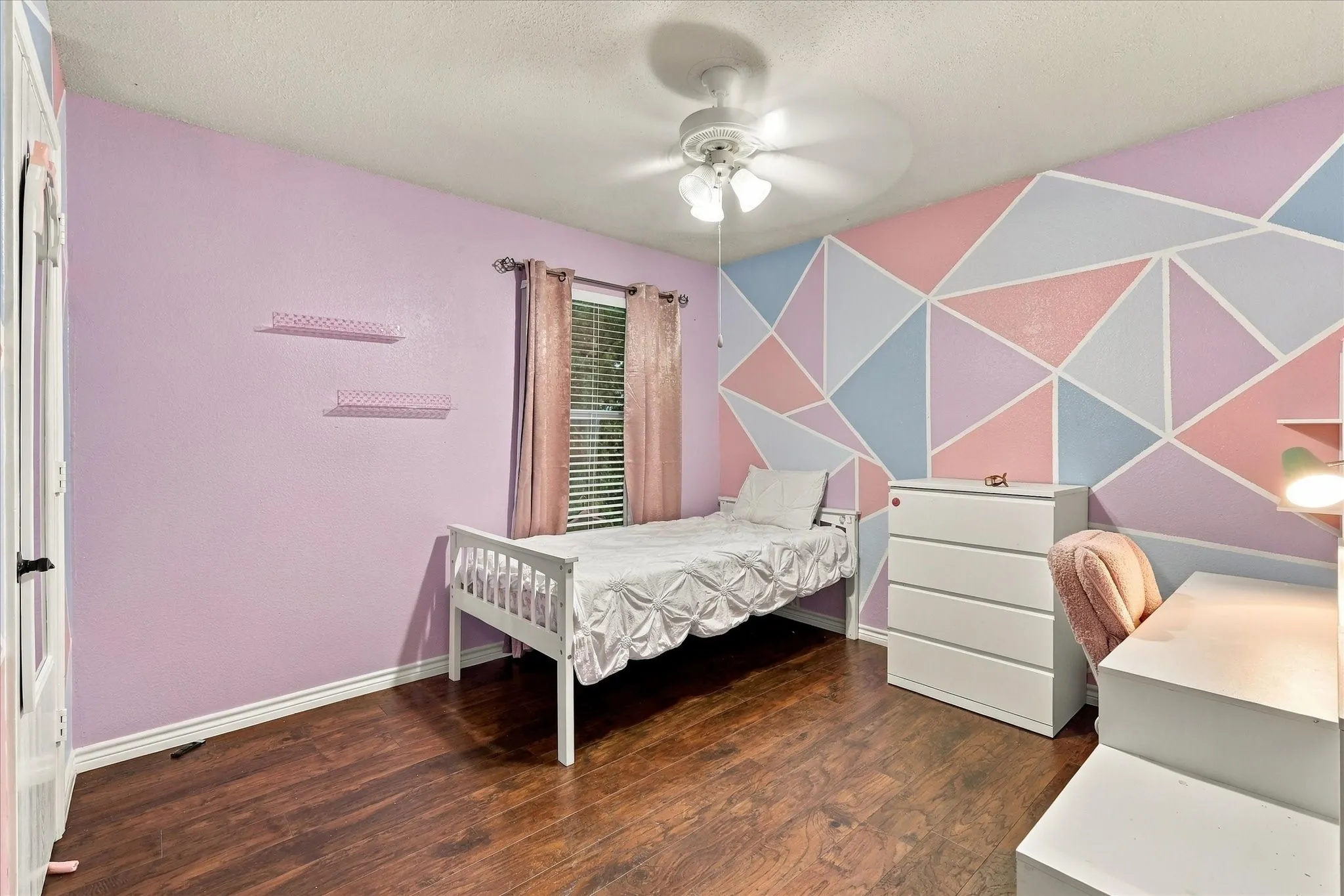 Wood-finish flooring, ceiling fan, and geometric accent wall