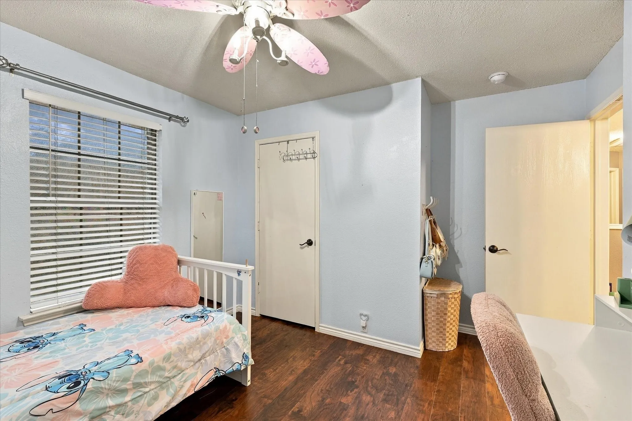 Wood-finish flooring, ceiling fan, and window with horizontal blinds