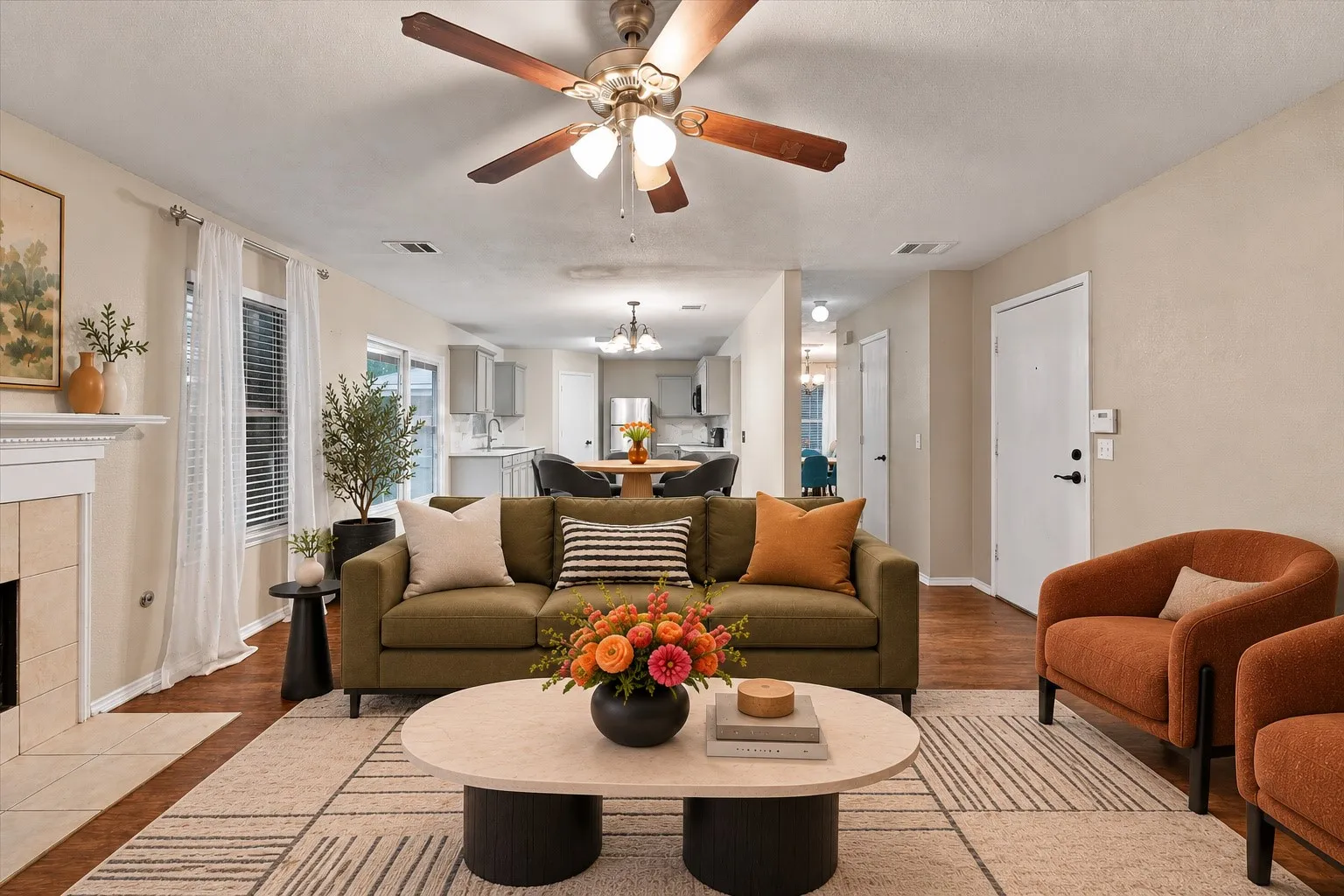 Virtually Staged Living area featuring wood-finish flooring, a ceiling fan with integrated lighting, and a fireplace with a tile surround and mantel