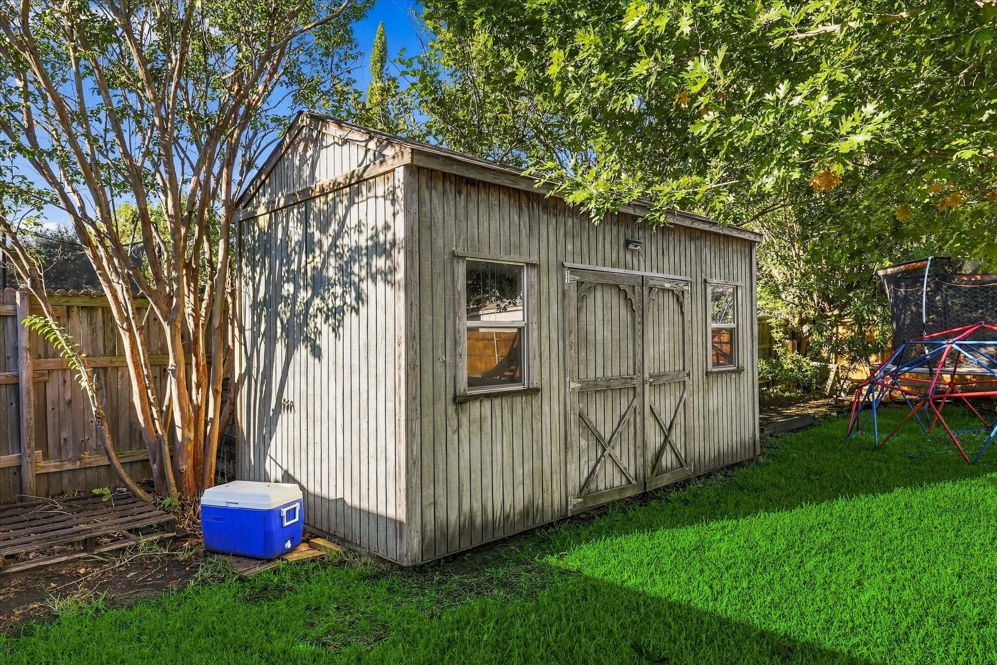 Wood-sided storage shed with double doors and dual windows