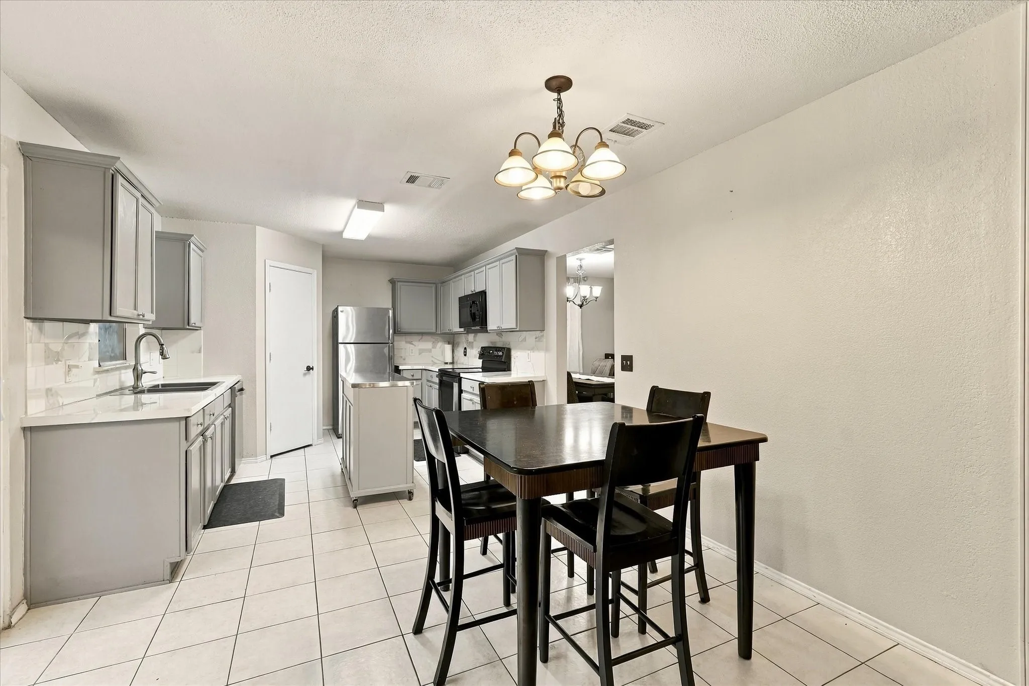 Kitchen with tile flooring, light gray cabinetry, white countertops, and a full suite of stainless steel appliances