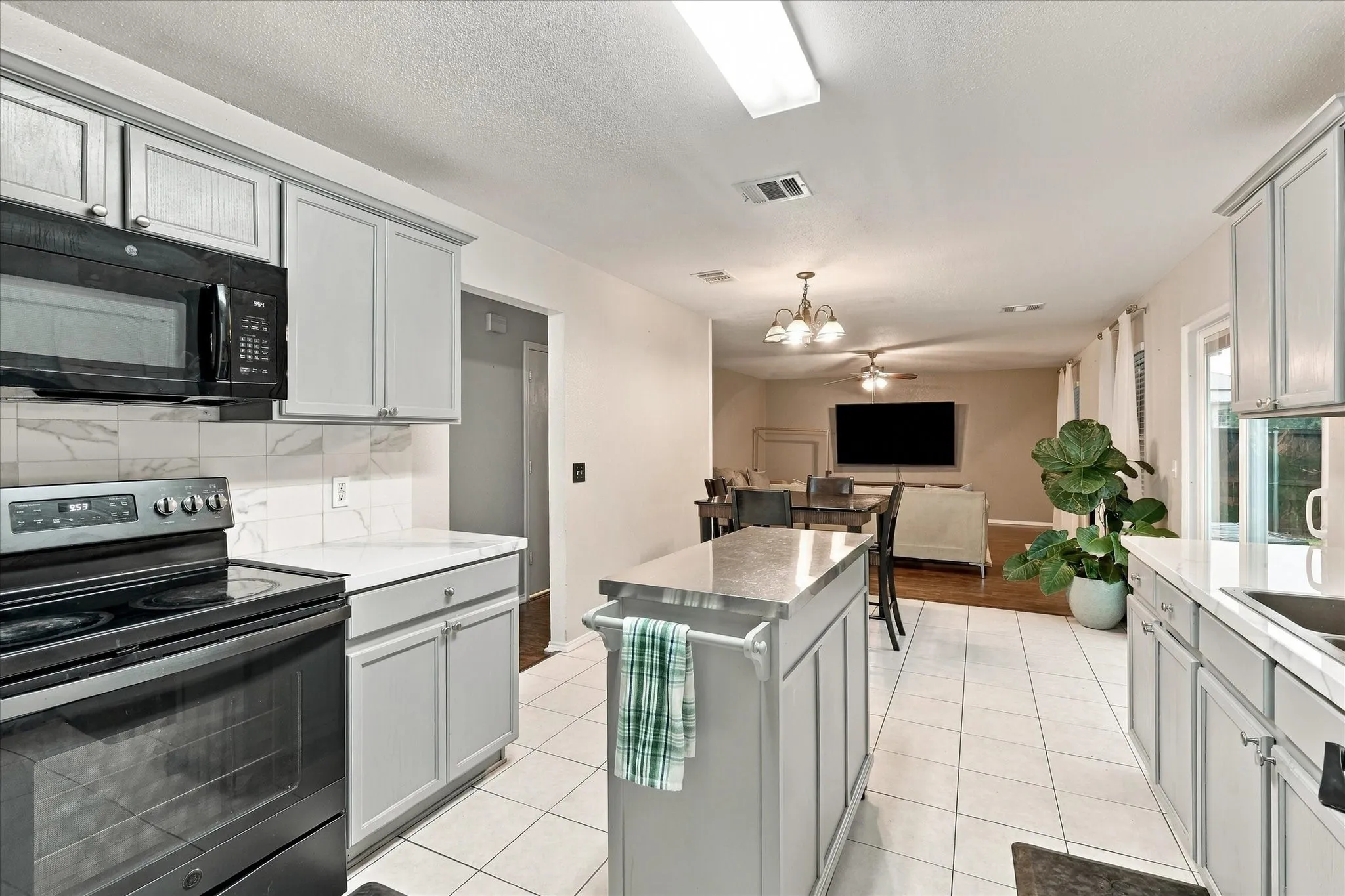 Kitchen featuring an island, light-toned cabinetry, tile flooring, and a stone-finish countertop